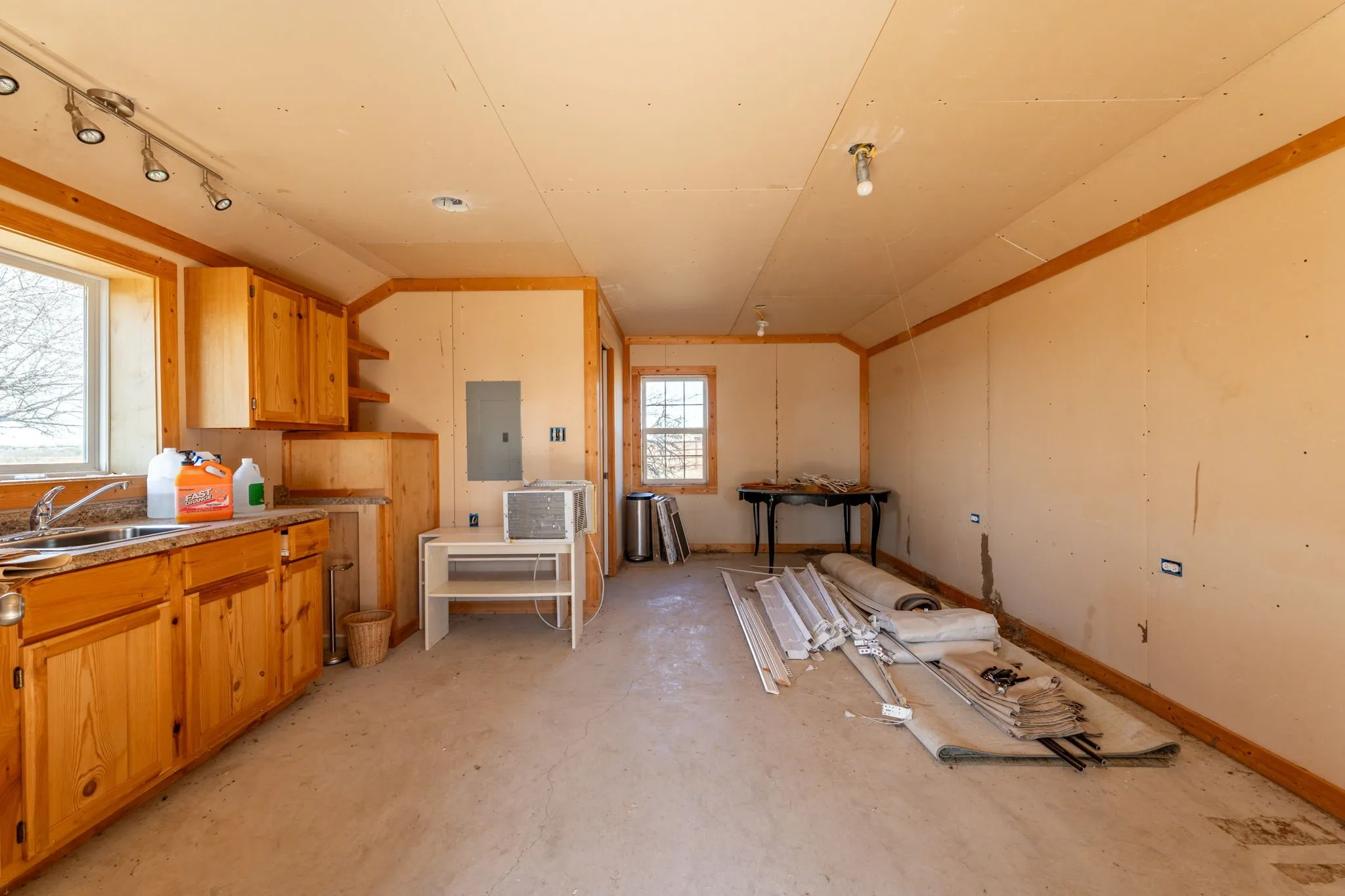 Open-concept space featuring natural wood cabinetry, a built-in sink with granite-style countertops, and track lighting