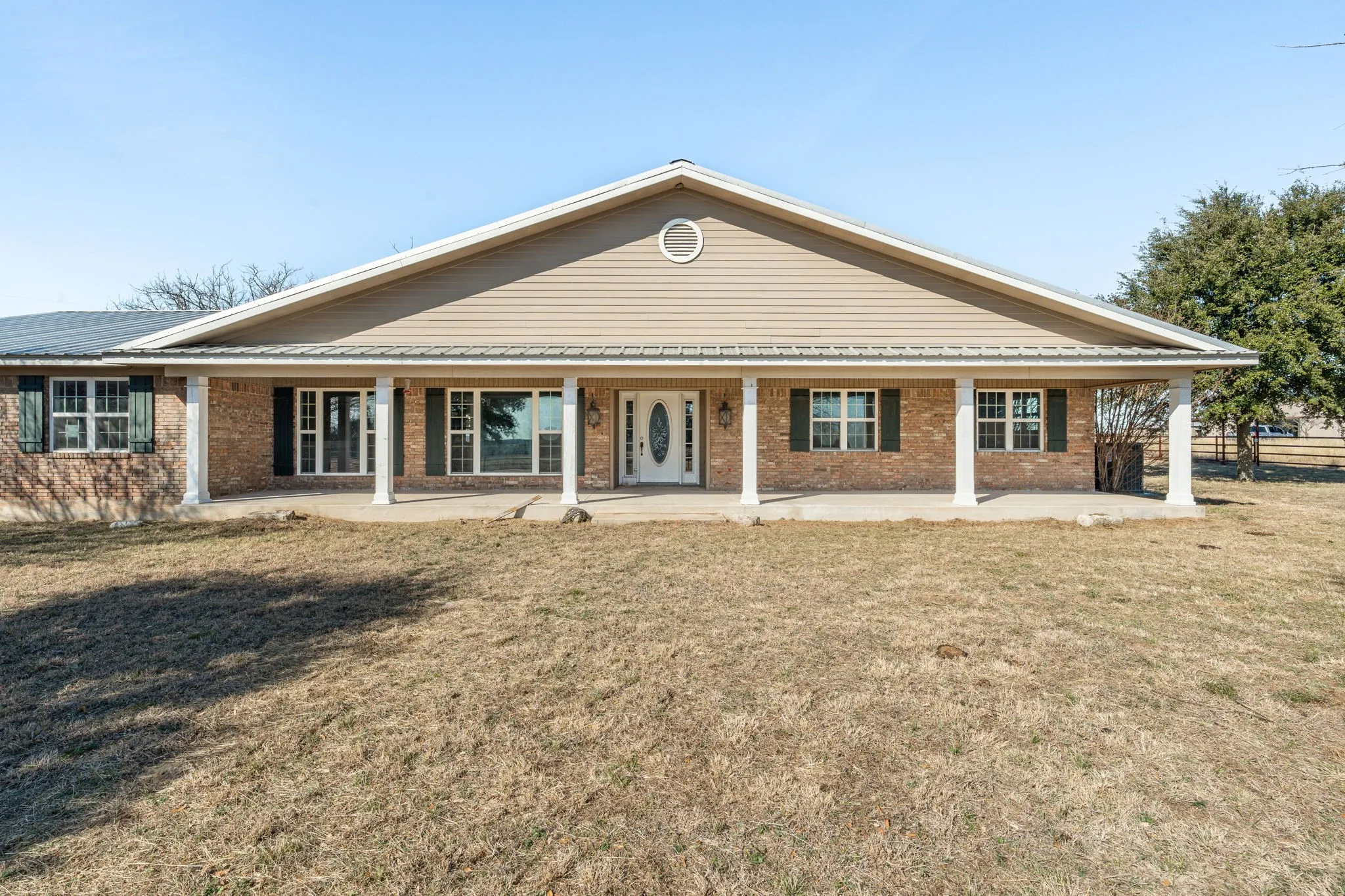 Brick and siding exterior featuring a covered front porch with white columns