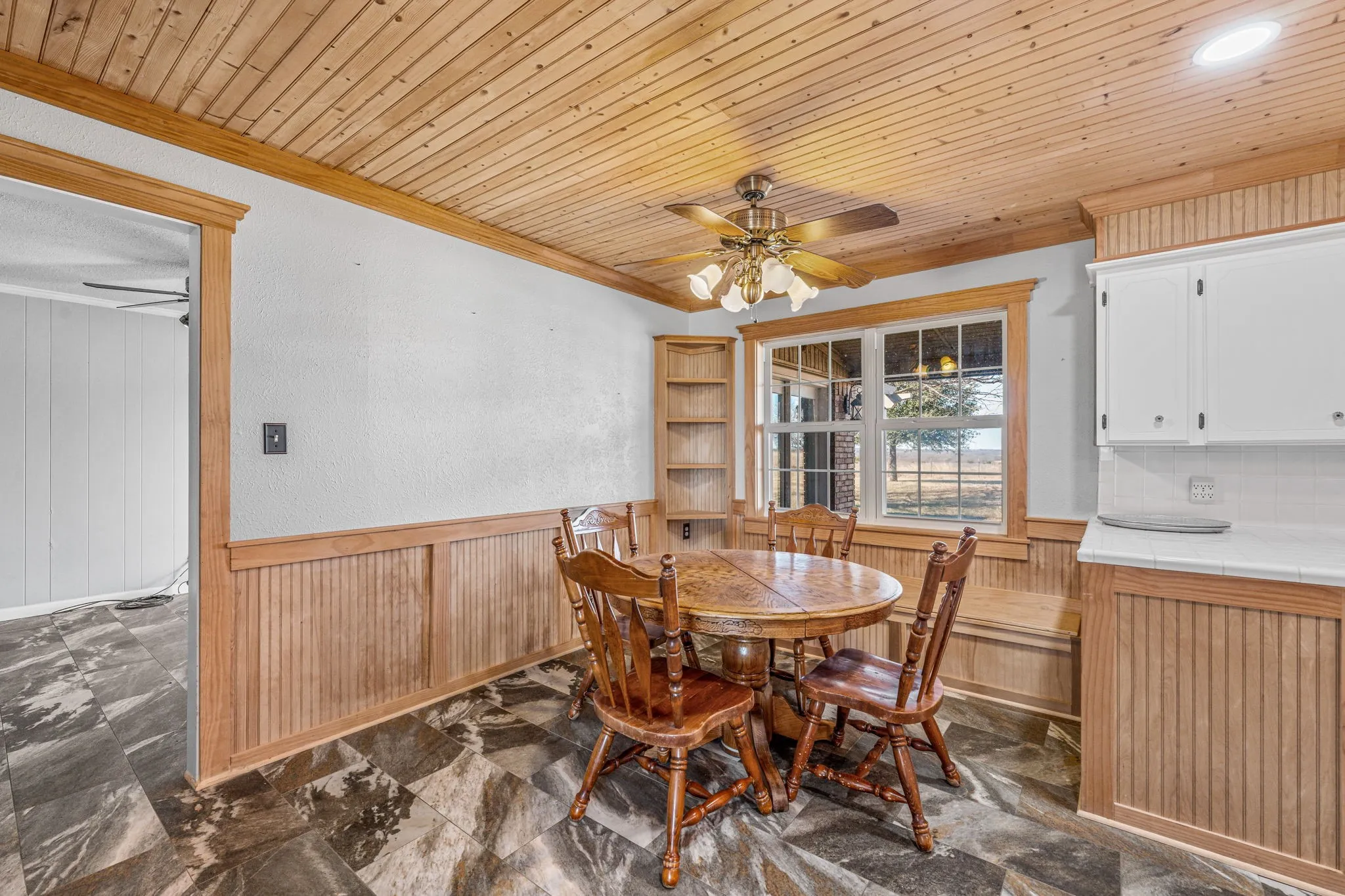 Wood-paneled ceiling with a central ceiling fan
