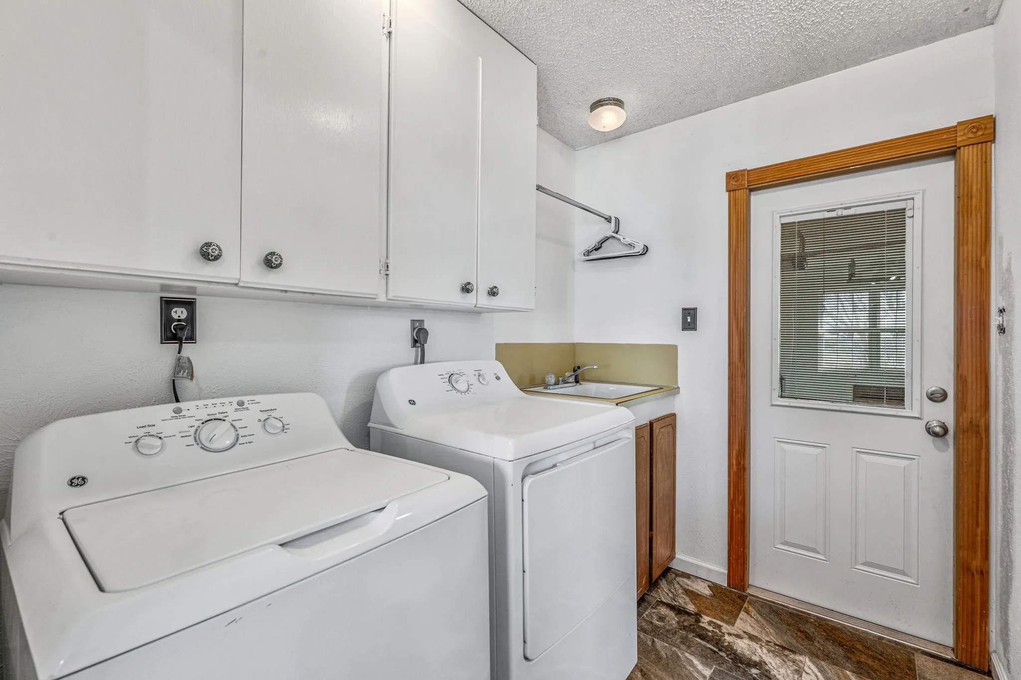 Laundry area featuring white cabinetry, a utility sink with a single-handle faucet, and a hanging rod