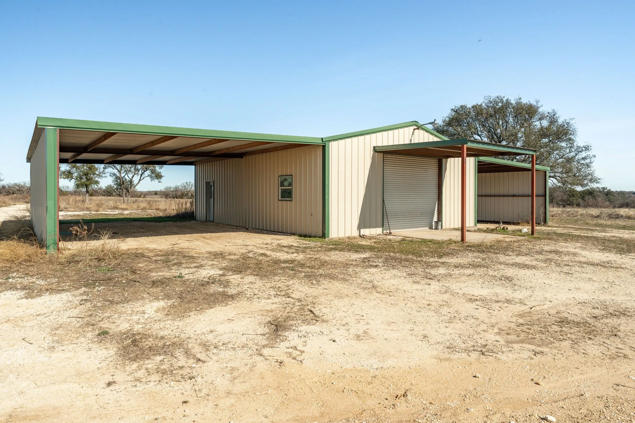 Metal utility building featuring a corrugated metal exterior, green trim, and multiple covered parking bays