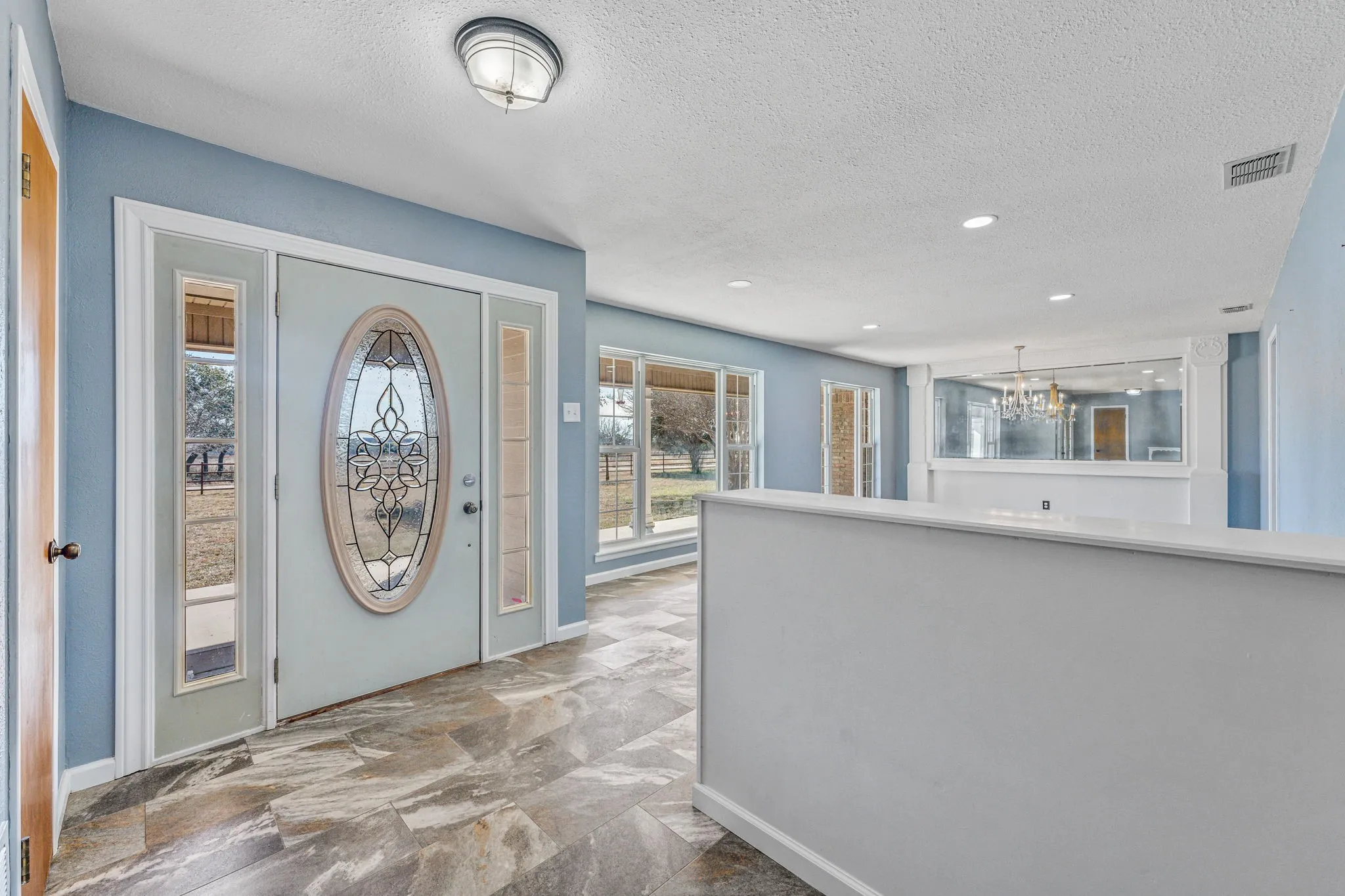 Entryway featuring a decorative oval glass door with sidelights, tile flooring, and light blue wall tones