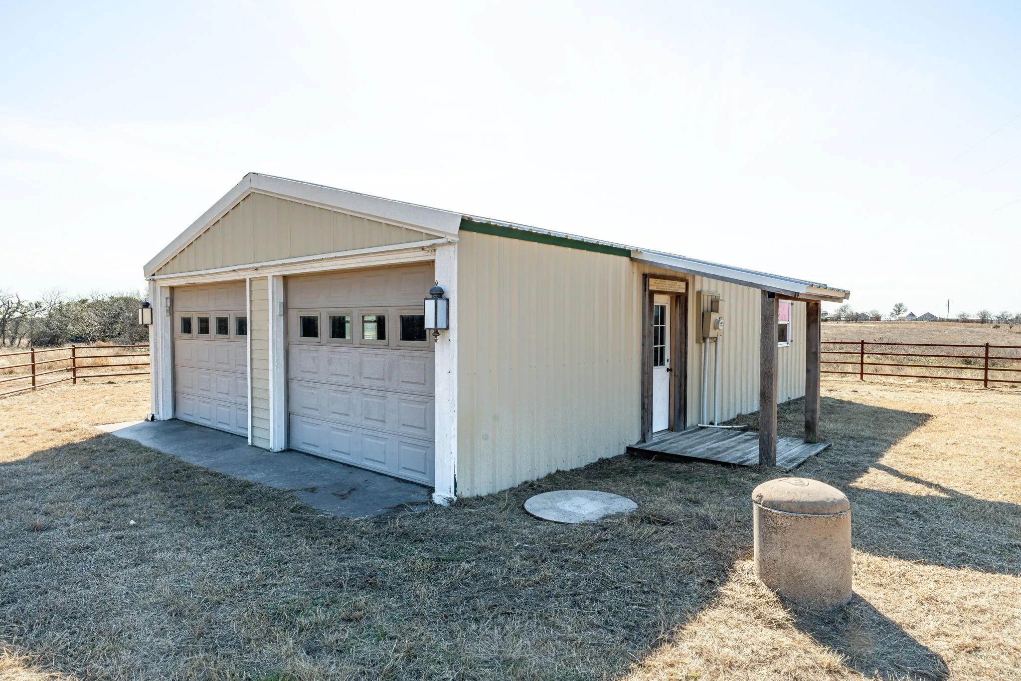 Detached garage structure featuring two overhead doors with window panels and exterior lighting fixtures