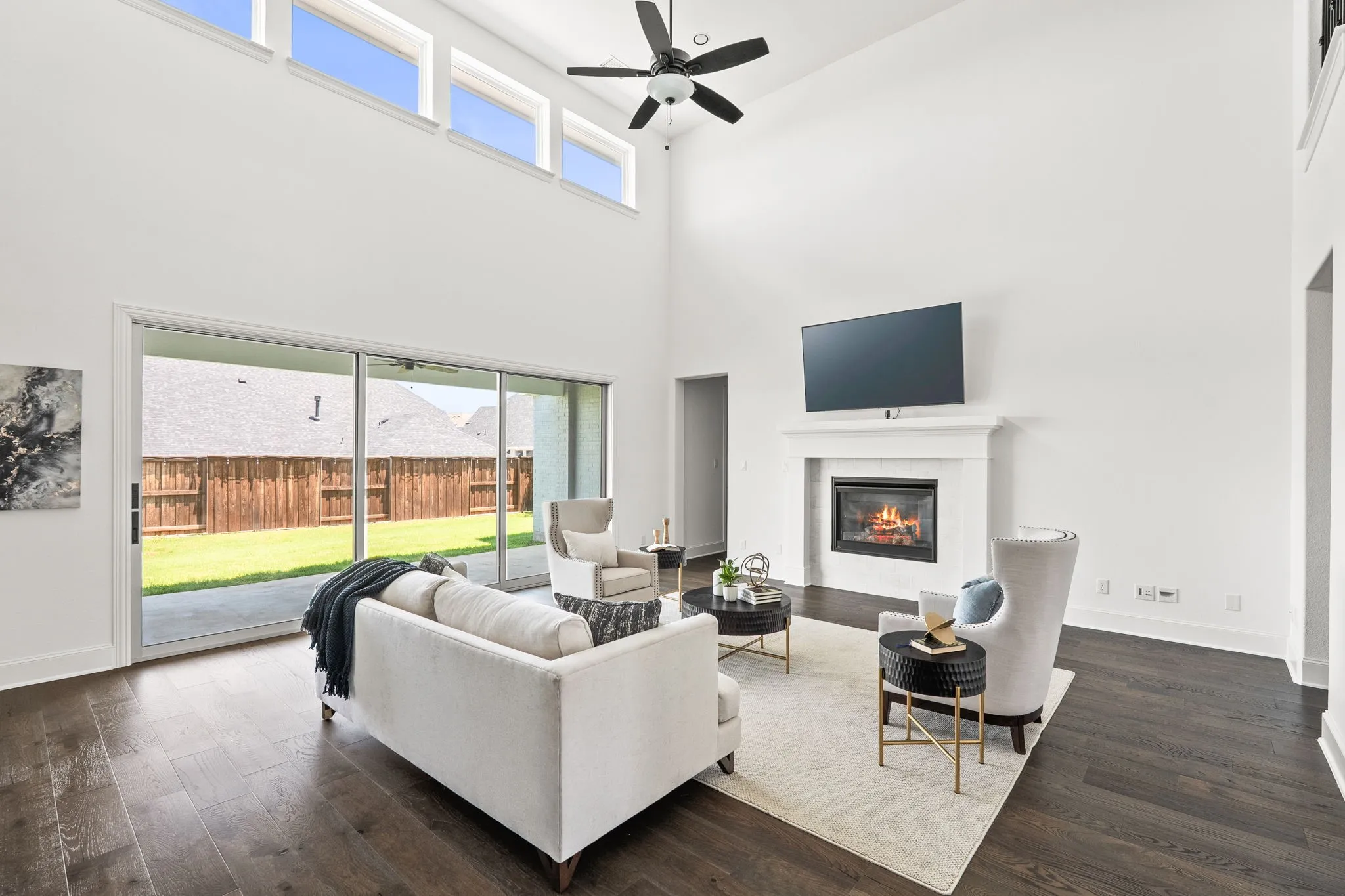 Spacious living area featuring a vaulted ceiling, dark wood-finish flooring, and a built-in fireplace with a white mantel