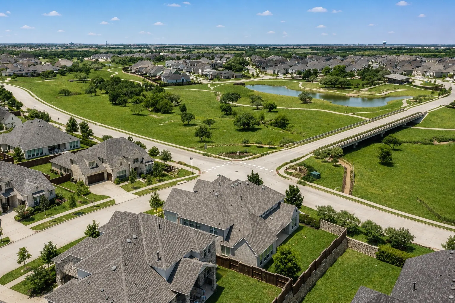 Residential neighborhood featuring a pond, bridge, and extensive green spaces