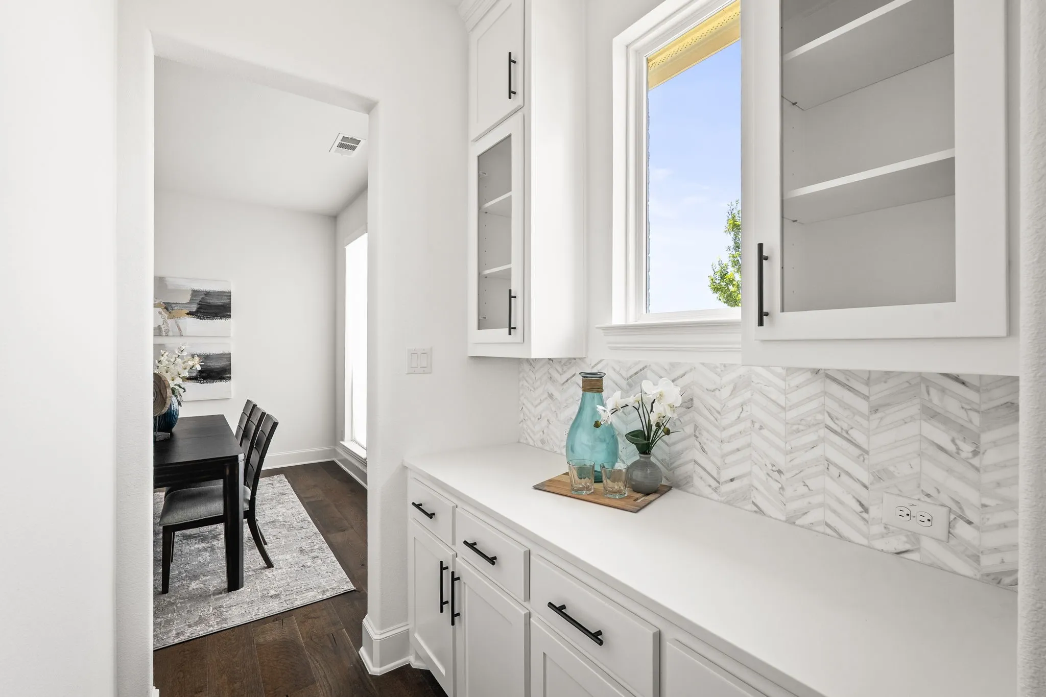 Custom built-in cabinetry featuring white shaker-style doors, glass-front upper cabinets, and matte black hardware