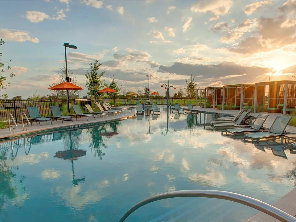 Resort-style swimming pool featuring a curved concrete deck, integrated lounge chairs, and private cabanas