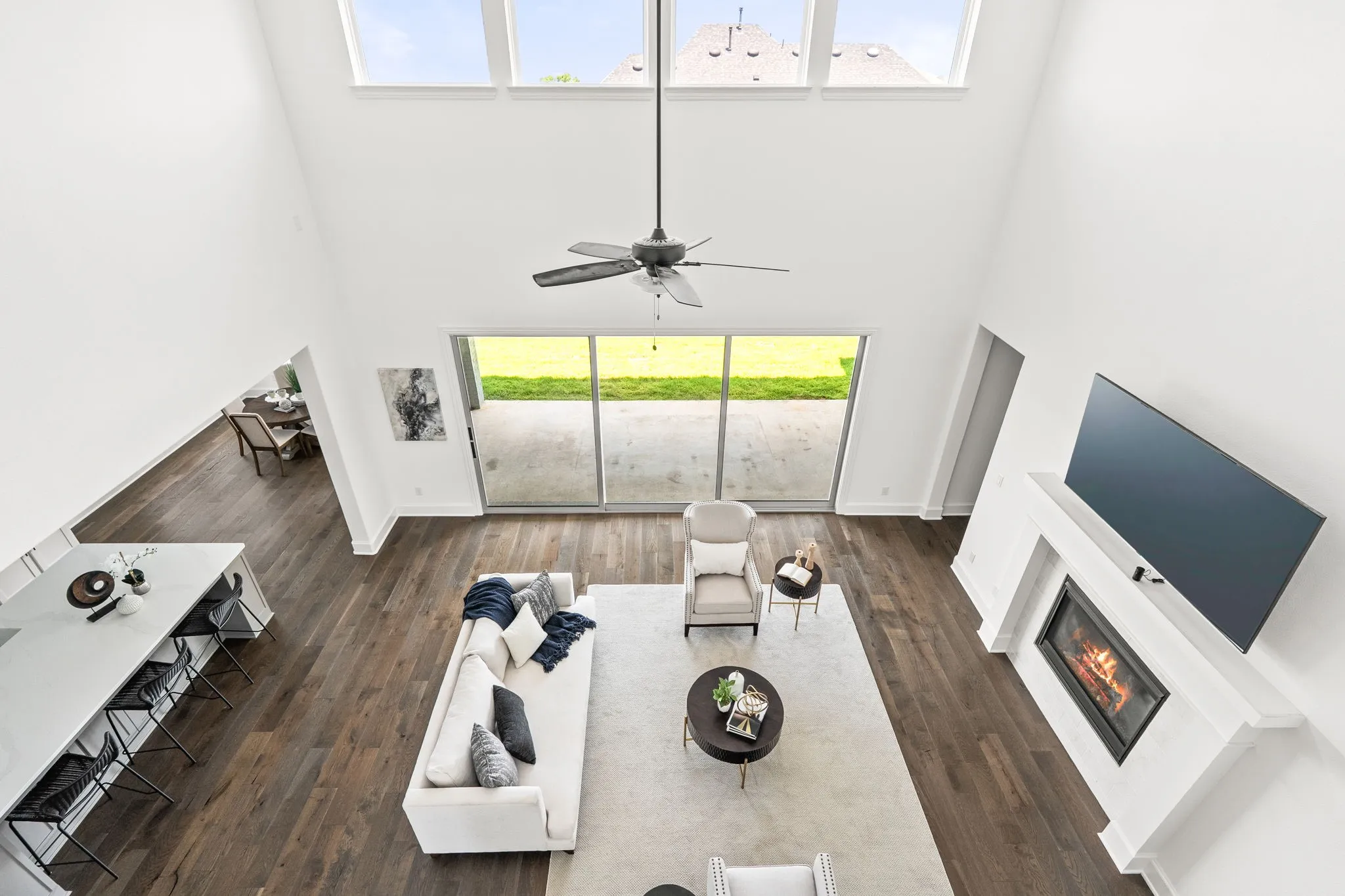Expansive living space featuring a soaring vaulted ceiling, upper transom windows, and wood-finish flooring