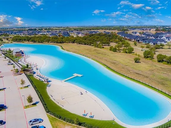 Expansive lagoon-style pool featuring sandy beaches, an extended dock, and a dedicated sand volleyball court