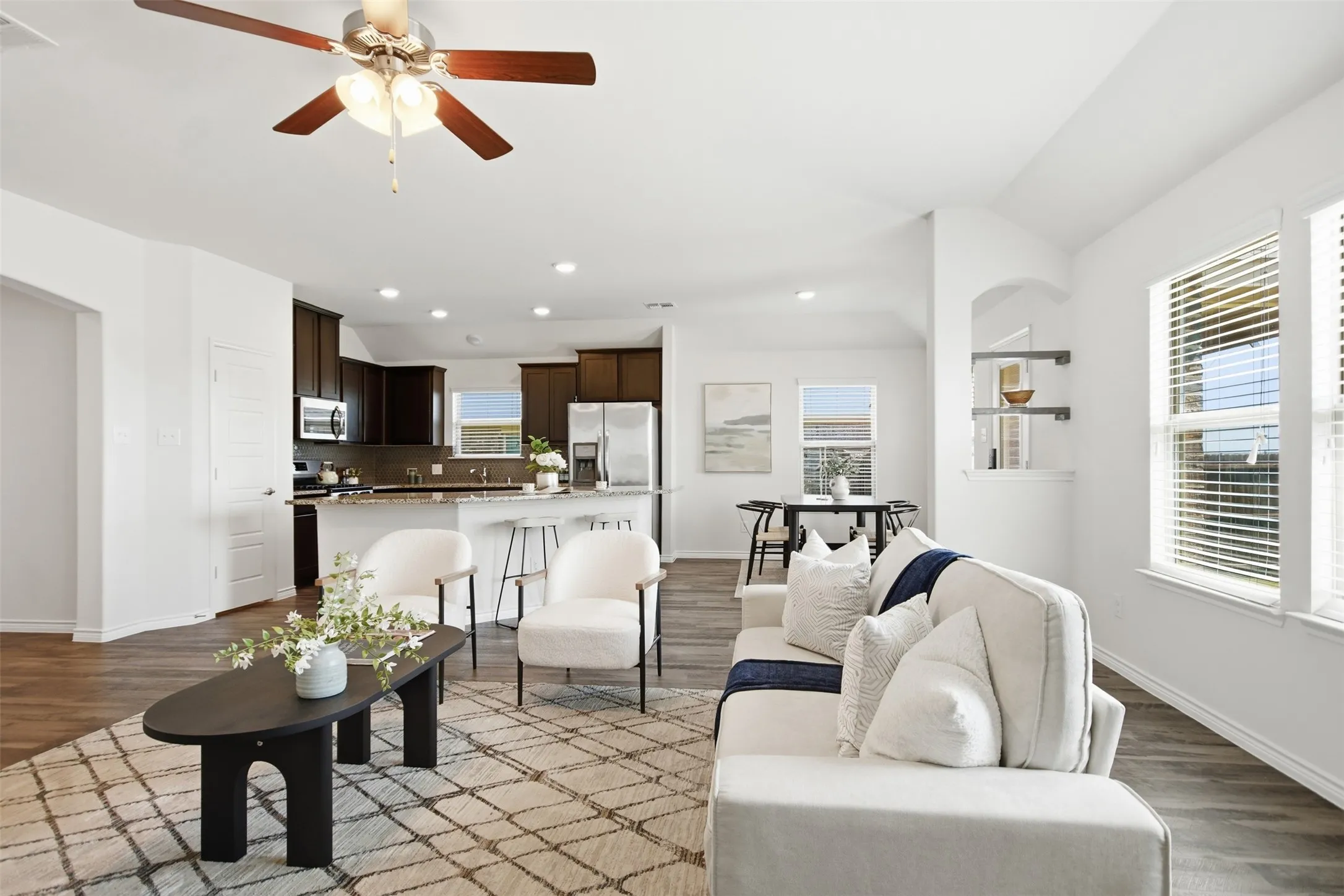 Open-concept living and dining area featuring recessed ceiling lighting, ceiling fan with brass accents, and wood-finish flooring throughout