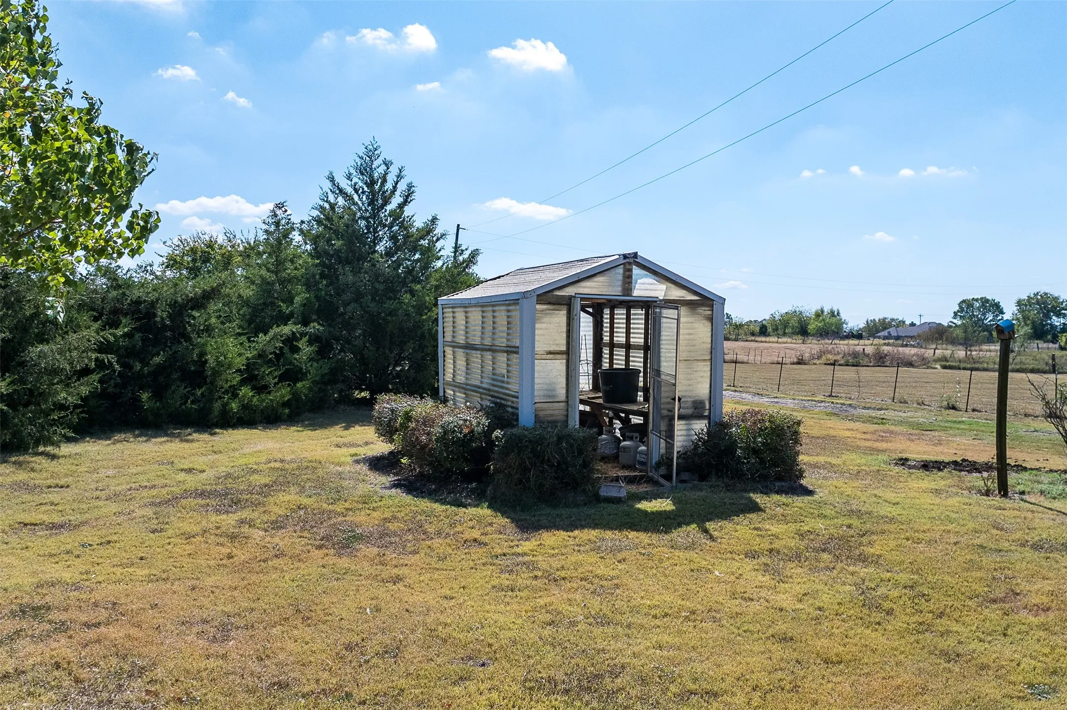 View of yard featuring a greenhouse, an outbuilding, and a rural view