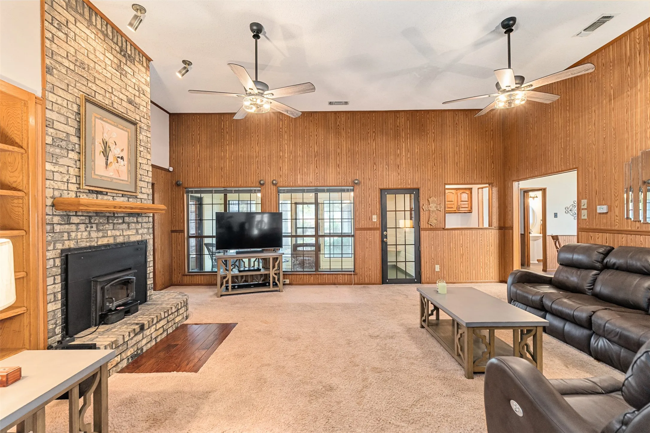 Living area with wooden walls, light colored carpet, and a wood stove