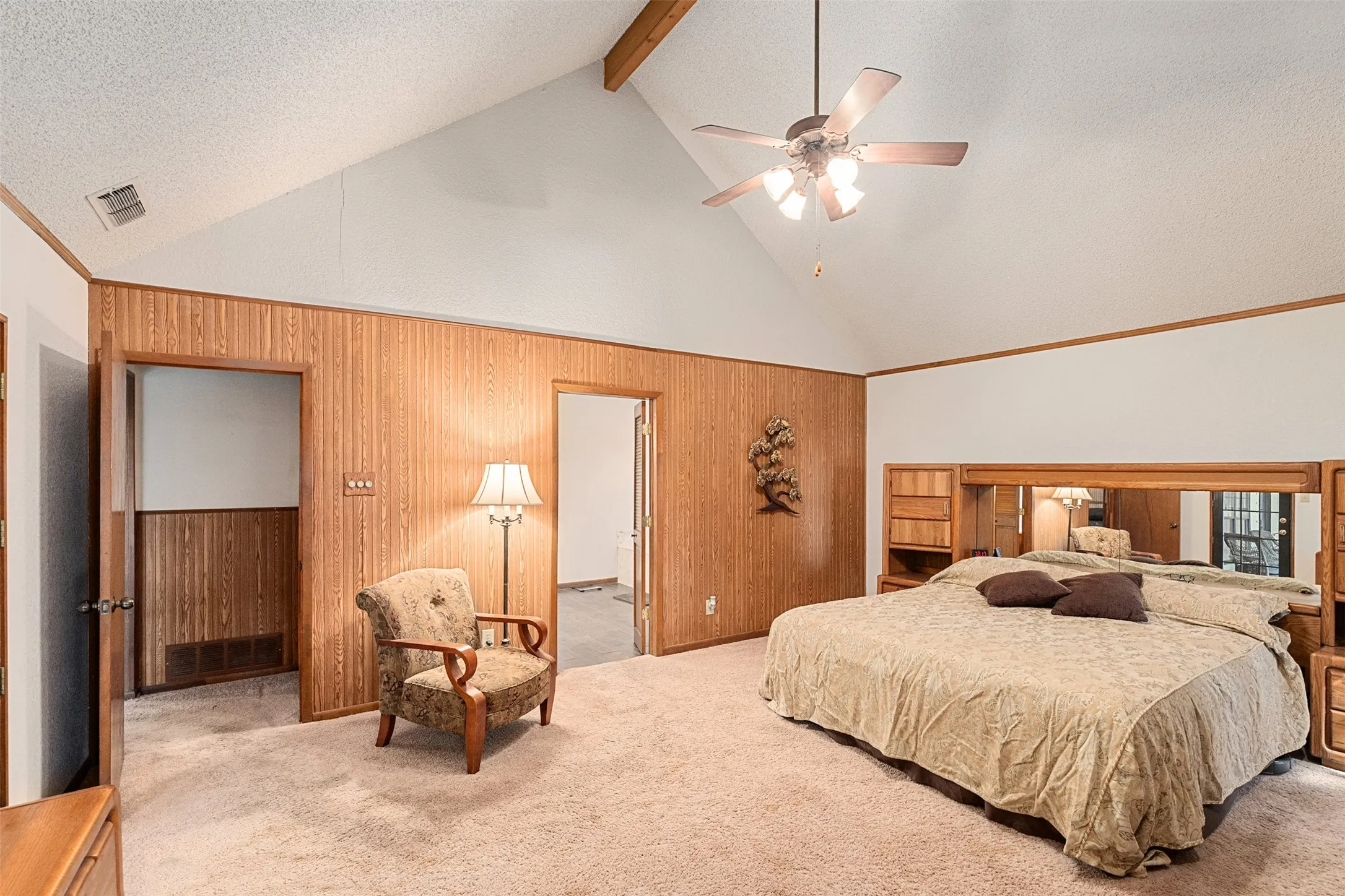 Carpeted bedroom with high vaulted ceiling, a textured ceiling, wood walls, a ceiling fan, and beam ceiling