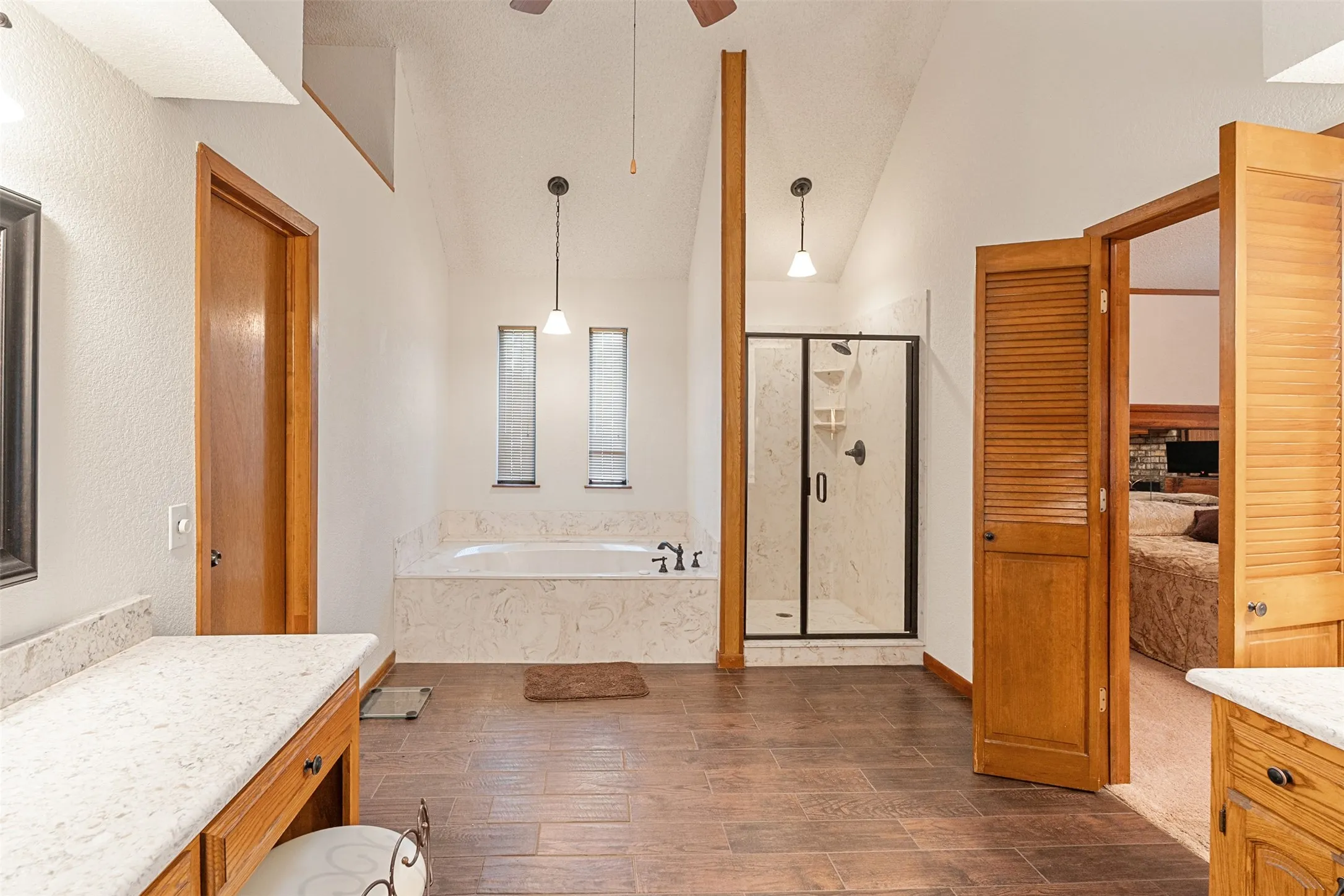 Primary full bath featuring a bath, a shower stall, vanity, dark wood-style flooring, and a ceiling fan