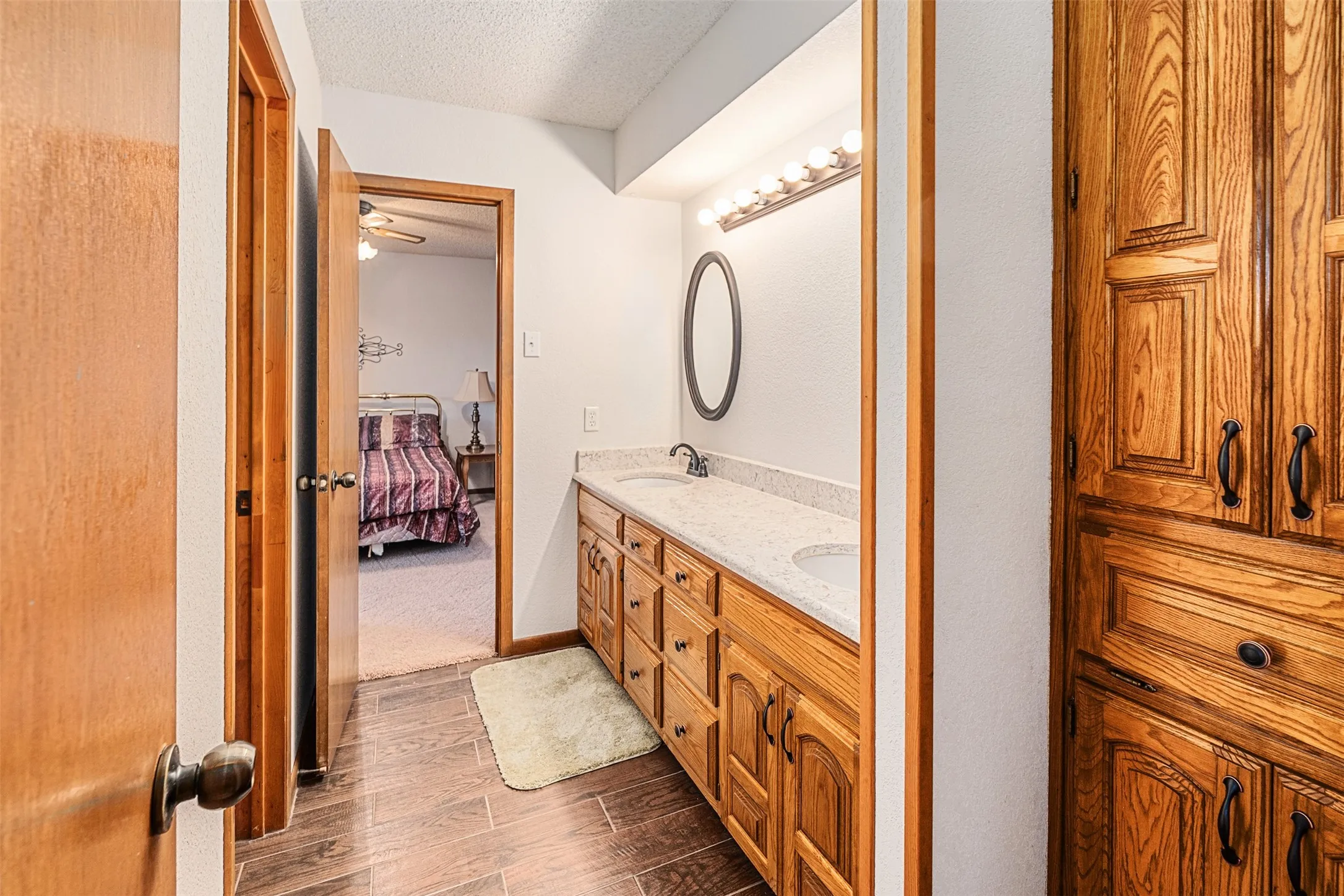 Full bathroom with a textured ceiling, double vanity, ensuite bathroom, wood tiled floors, and a ceiling fan