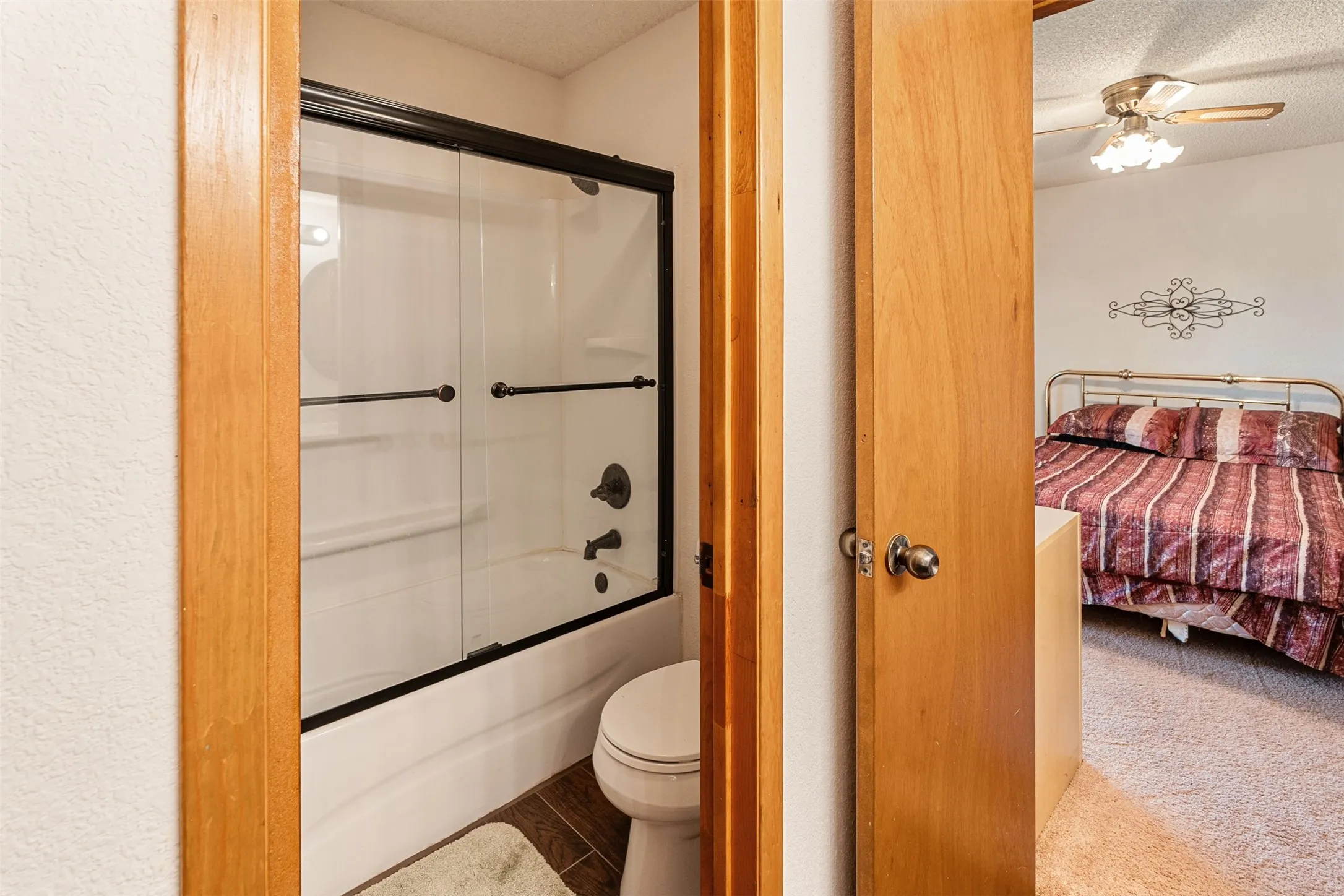Full bathroom featuring ensuite bath, combined bath / shower with glass door, a textured ceiling, ceiling fan, and carpet floors