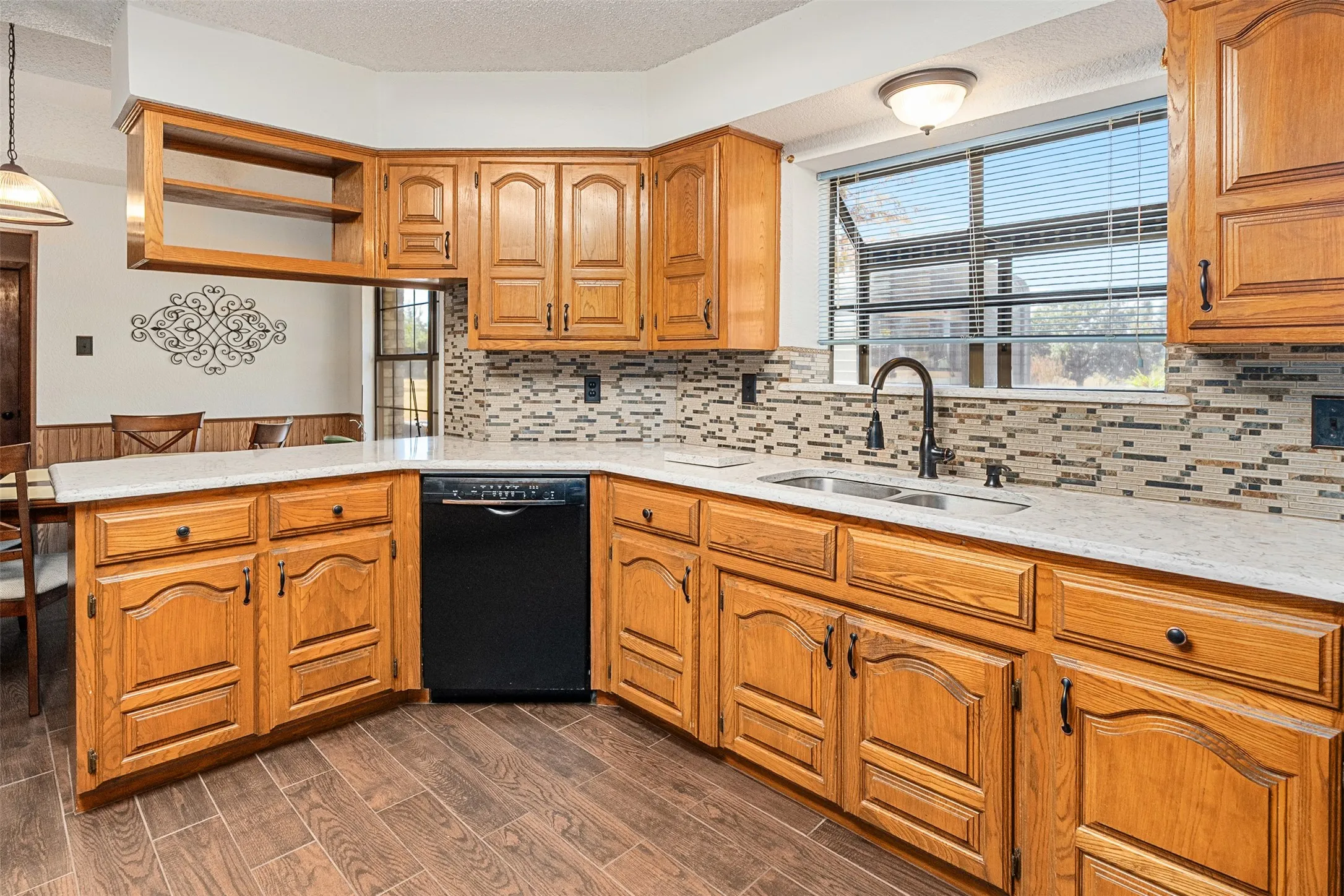 Kitchen with dishwasher, light stone countertops, open shelves, a peninsula, and a textured ceiling