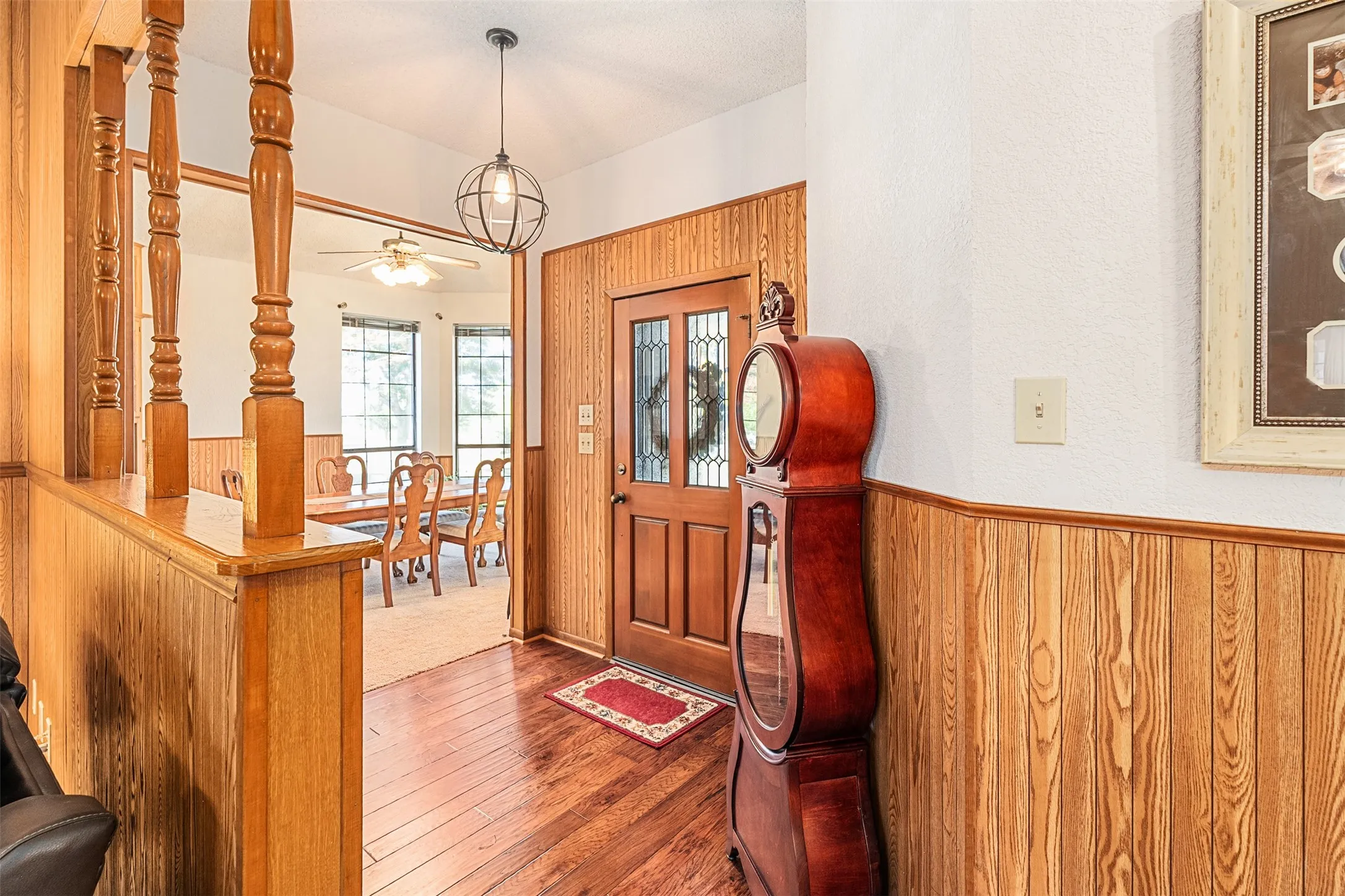 Entryway featuring wooden walls, dark wood-style floors, a wainscoted wall, and a ceiling fan