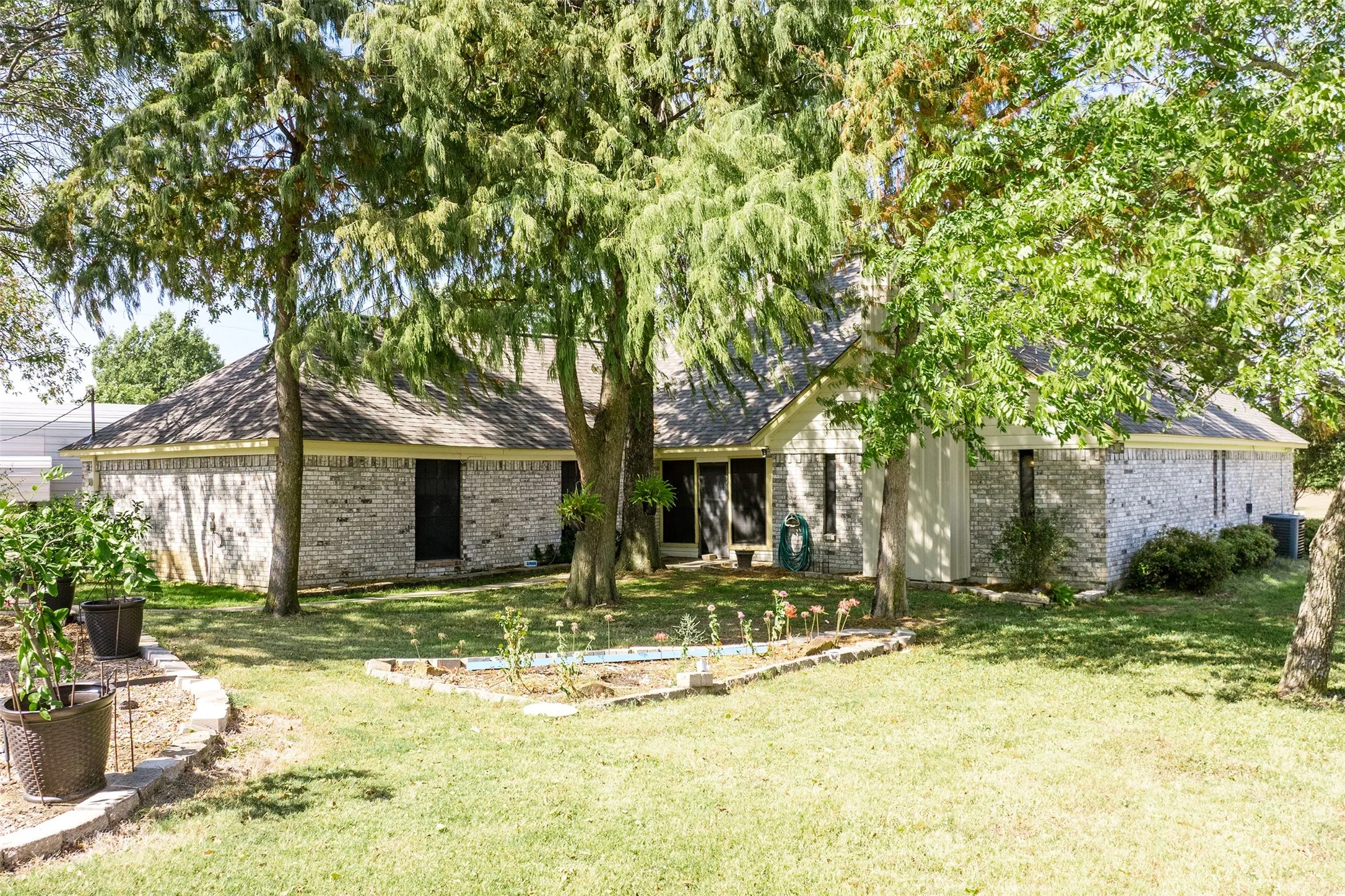 View of back of property with brick siding and a front yard