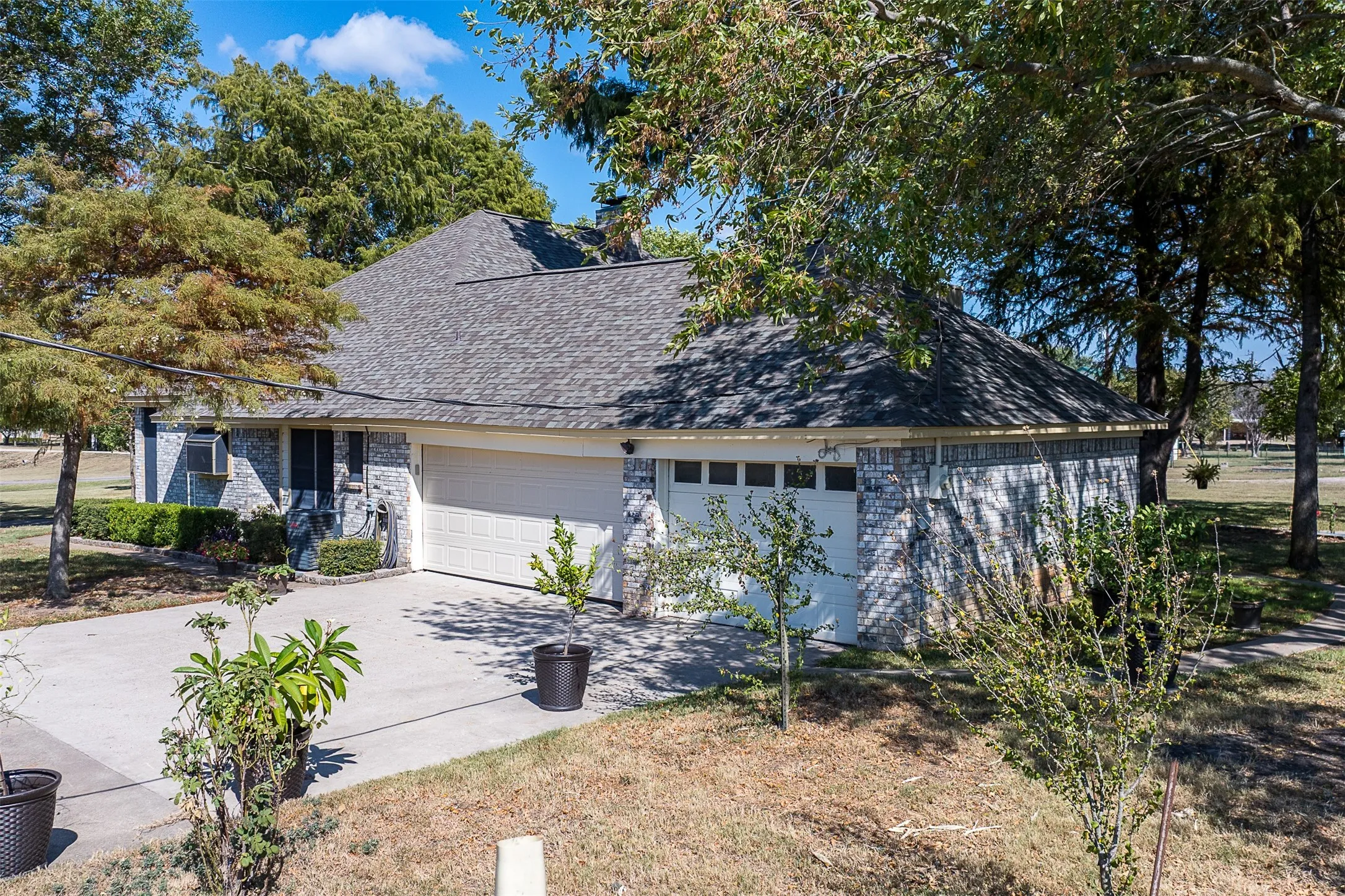 View of home's exterior featuring brick siding, concrete driveway, and roof with shingles