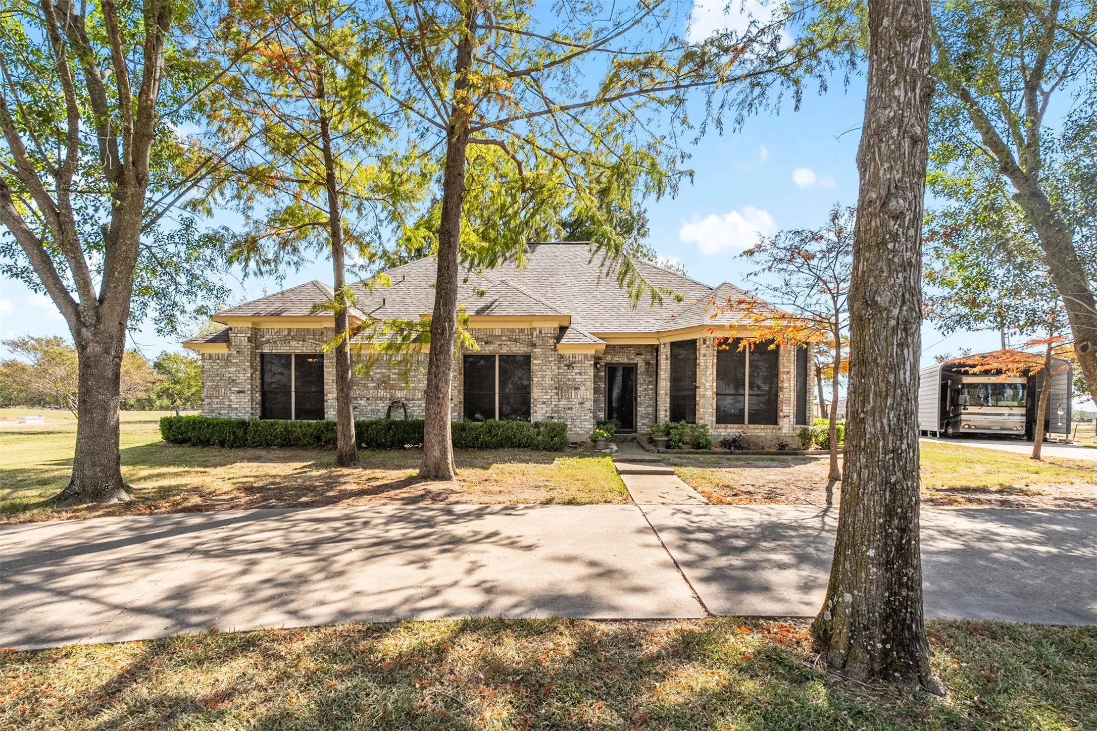 View of front of property with brick siding, a shingled roof, and a front yard