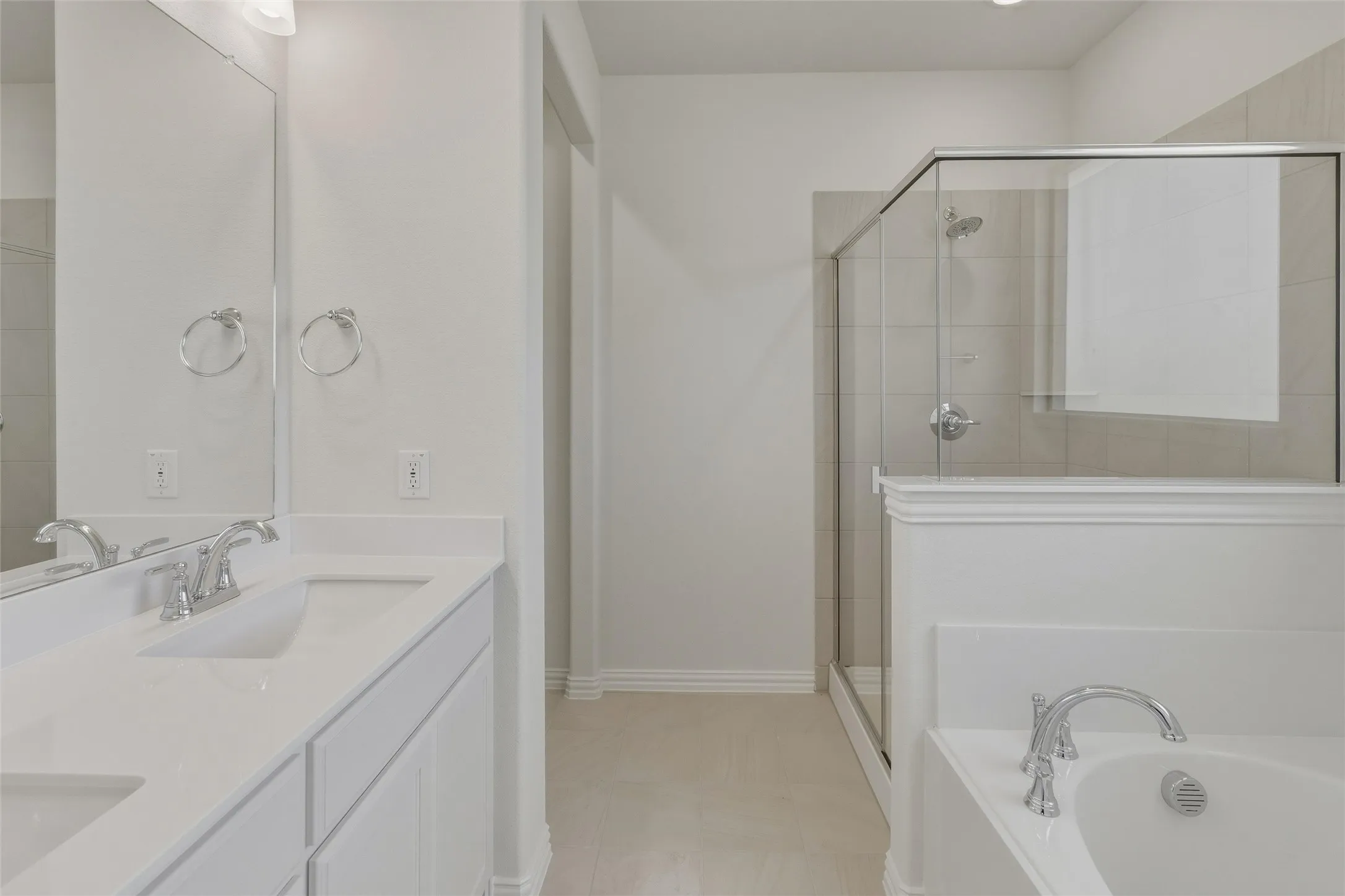 Bathroom featuring a dual vanity with undermount sinks, a walk-in shower with clear glass enclosure, a built-in soaking tub, and tile flooring