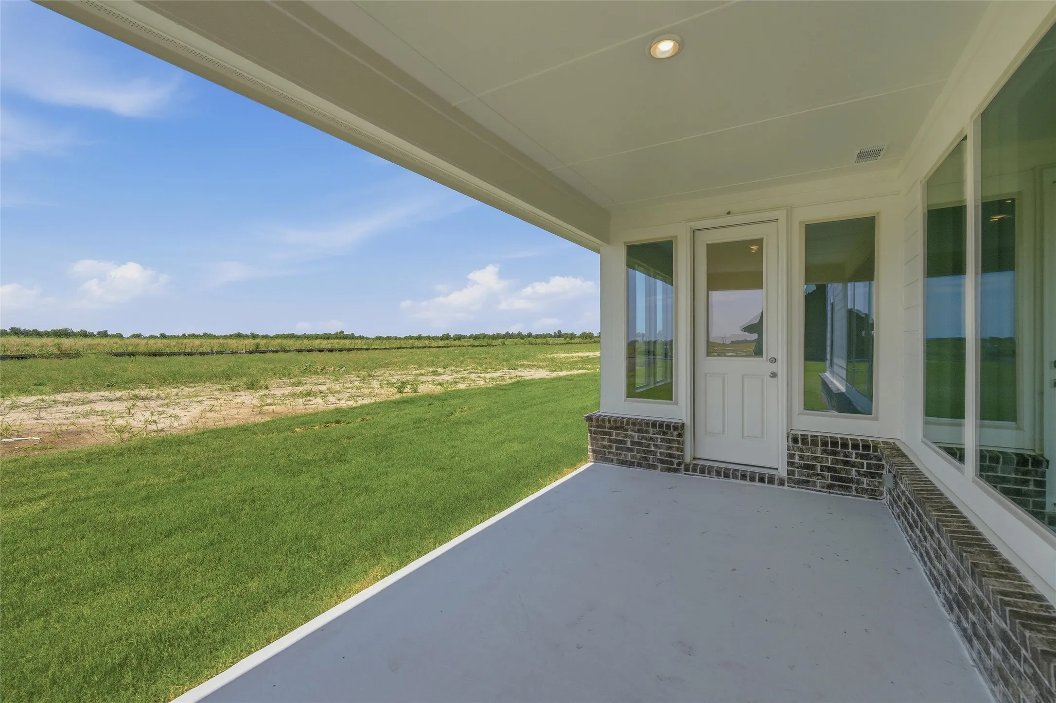 Covered patio featuring a concrete slab, recessed lighting, and a brick base