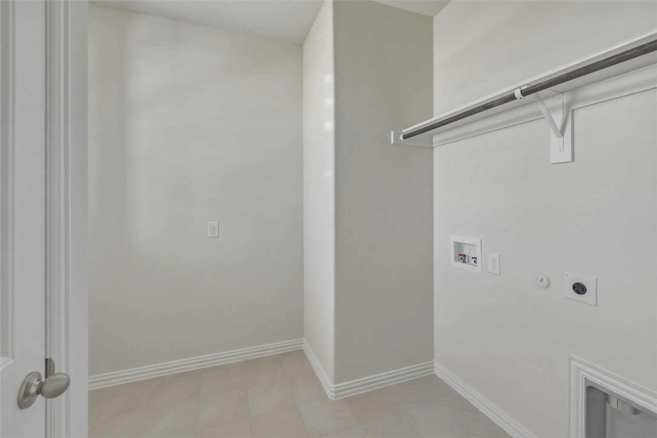 Dedicated utility area featuring tile flooring, neutral wall tones, and baseboard trim