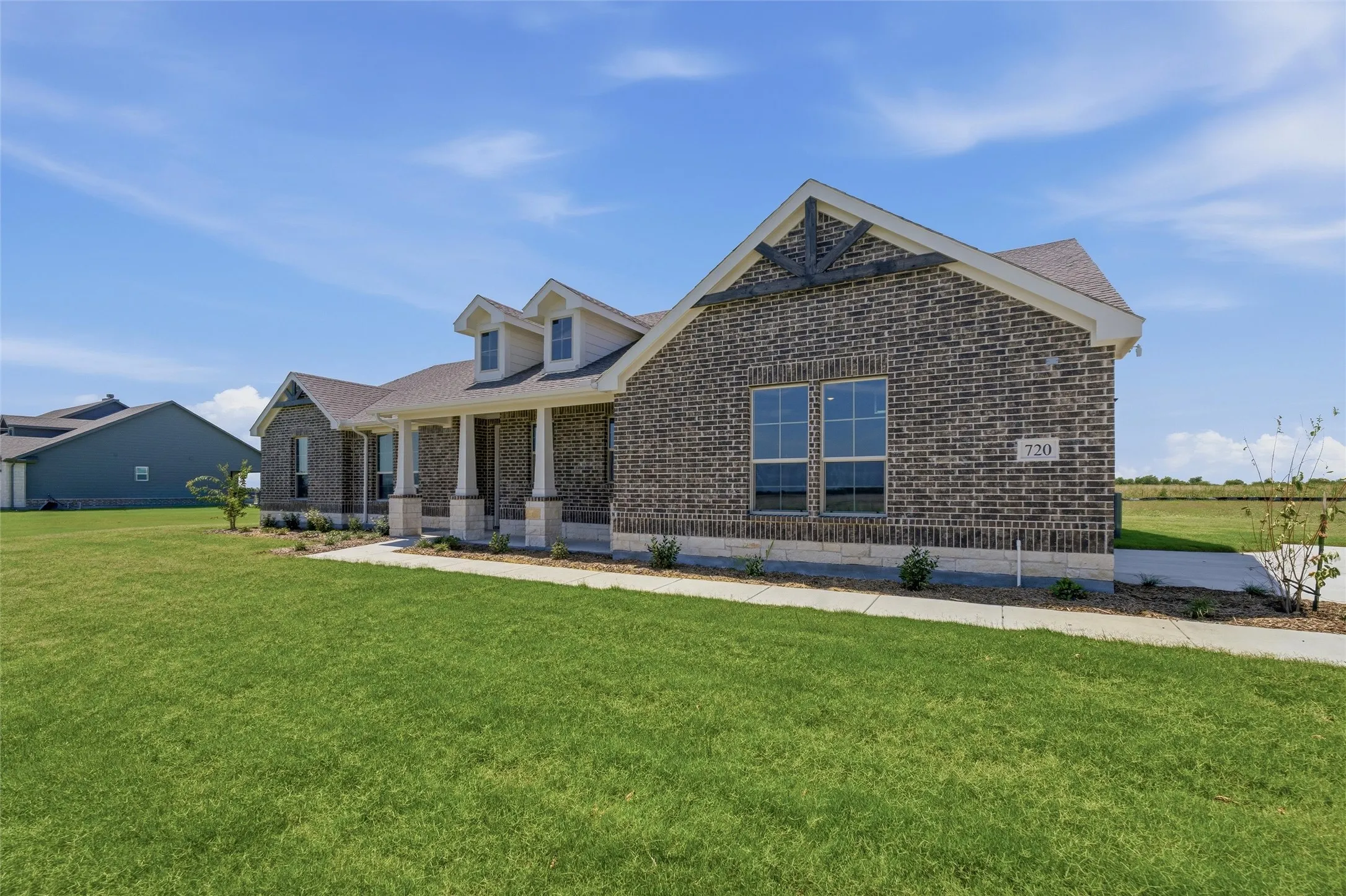 Brick exterior with light stone accents, featuring a covered front porch with multiple columns