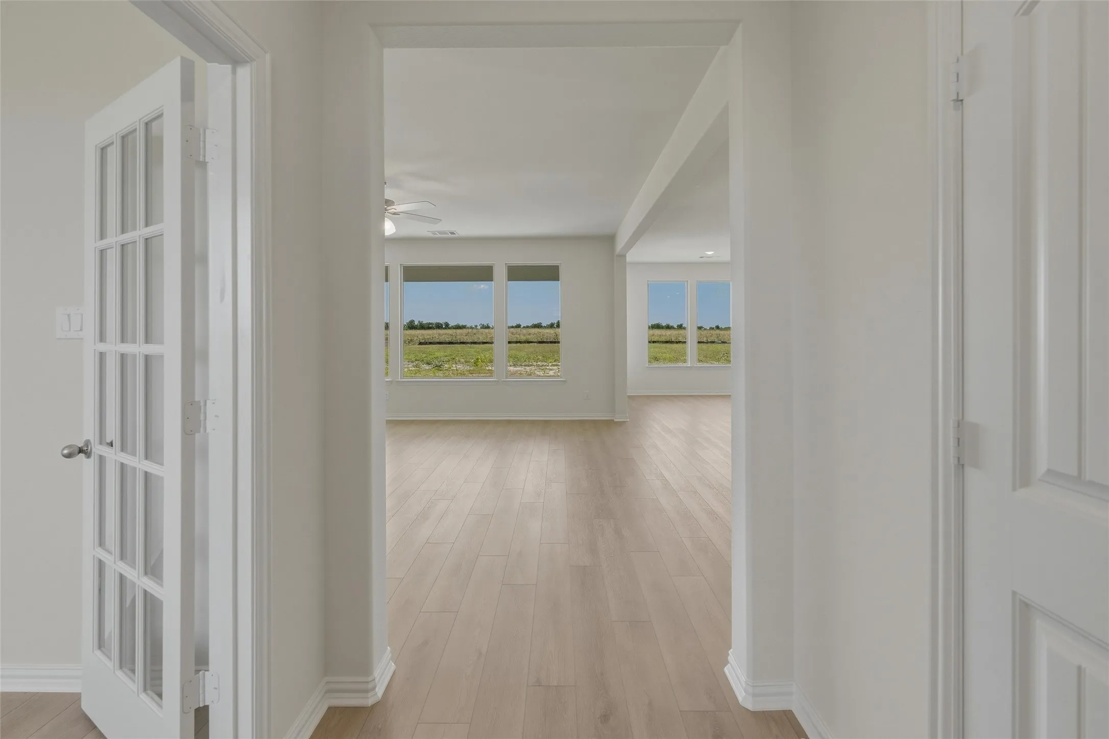 Entryway featuring a paneled interior door, a glass-paned French door, wood-finish flooring, and white baseboards