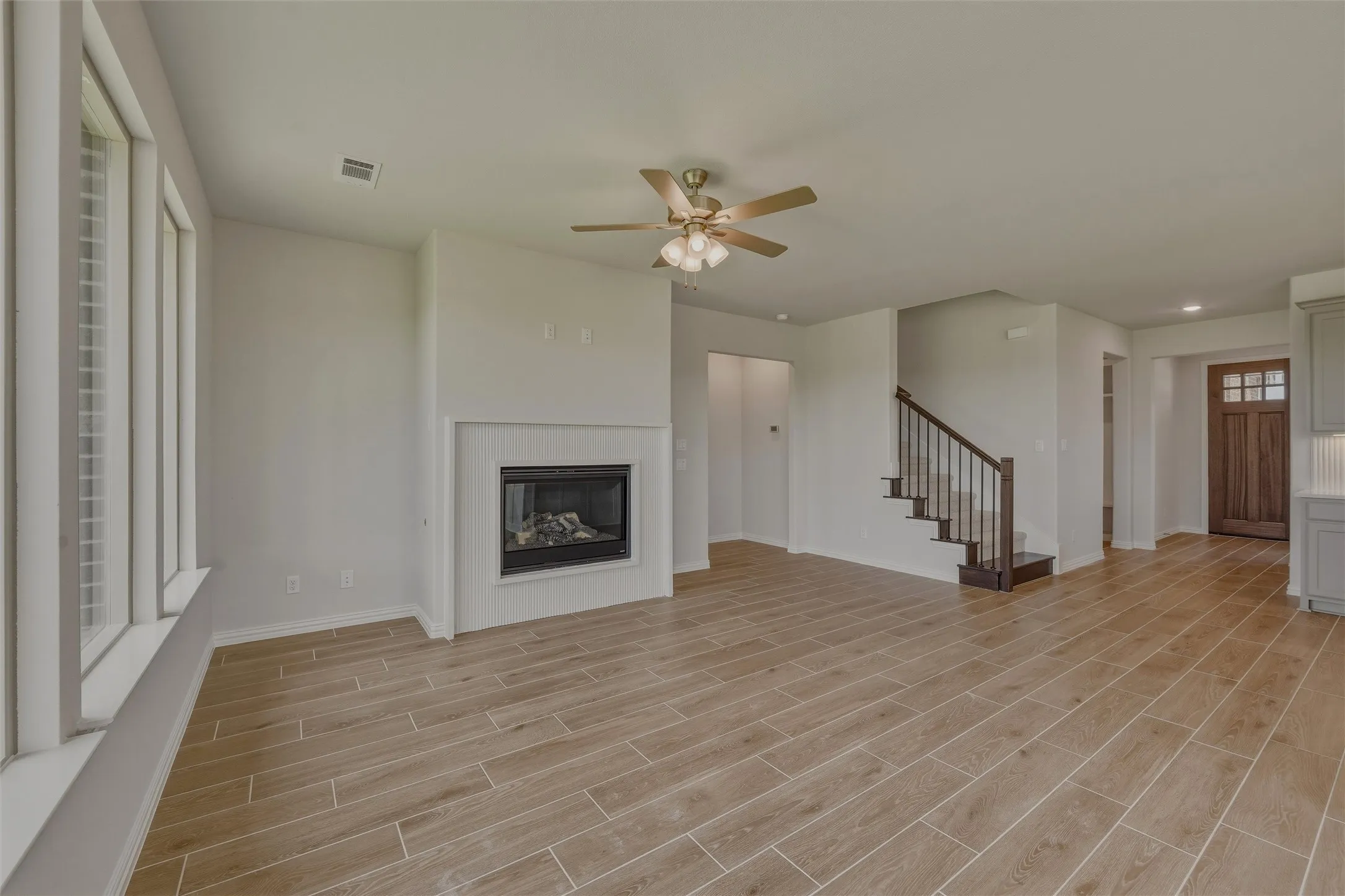 Living area featuring wood-finish tile flooring, a built-in fireplace with a white mantel, and a multi-pane window with interior shutters