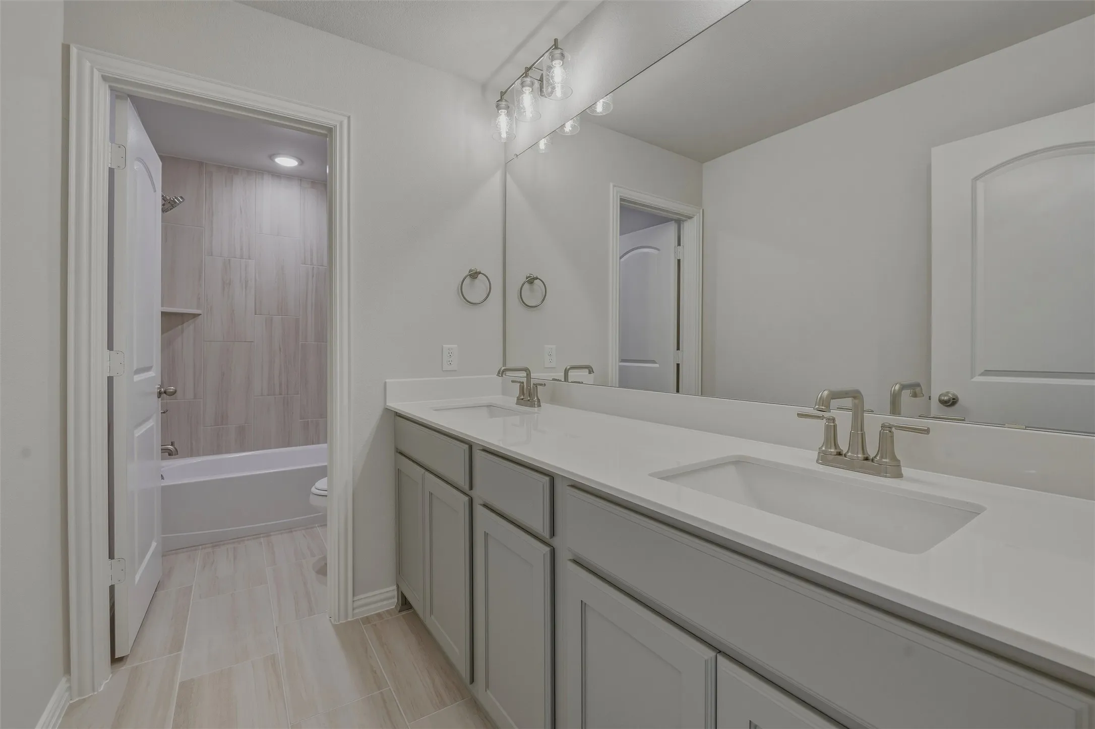 Bathroom featuring a dual vanity with light gray cabinetry, integrated sinks, and brushed nickel fixtures