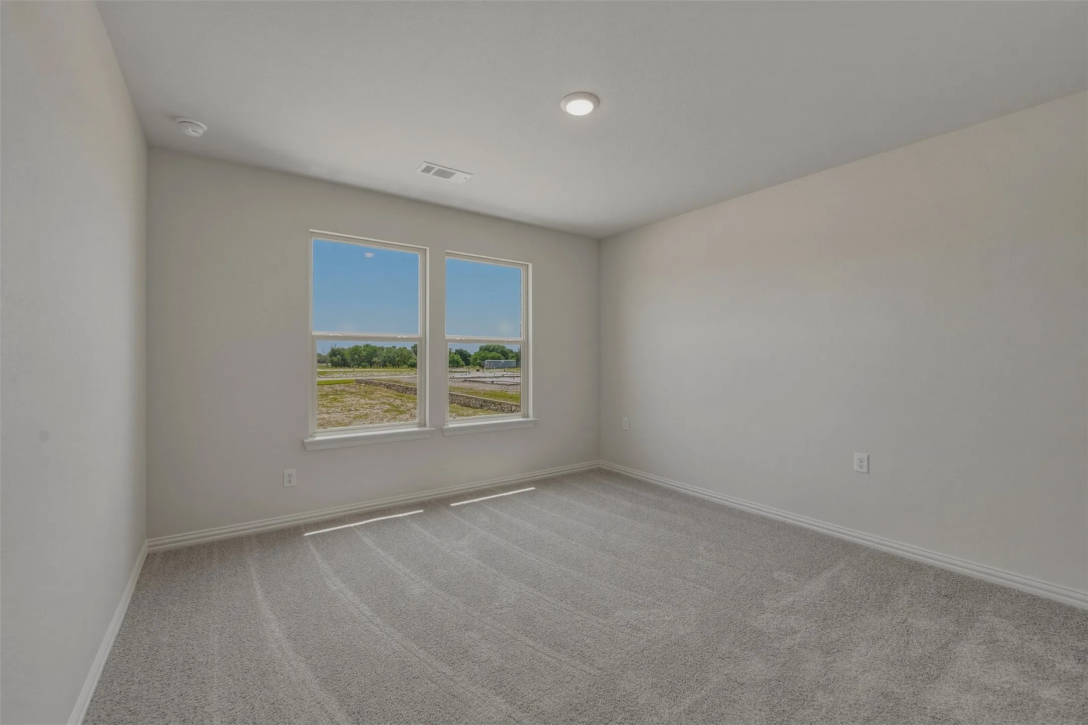 Room featuring two windows, recessed ceiling lighting, light gray wall paint, and gray carpeting