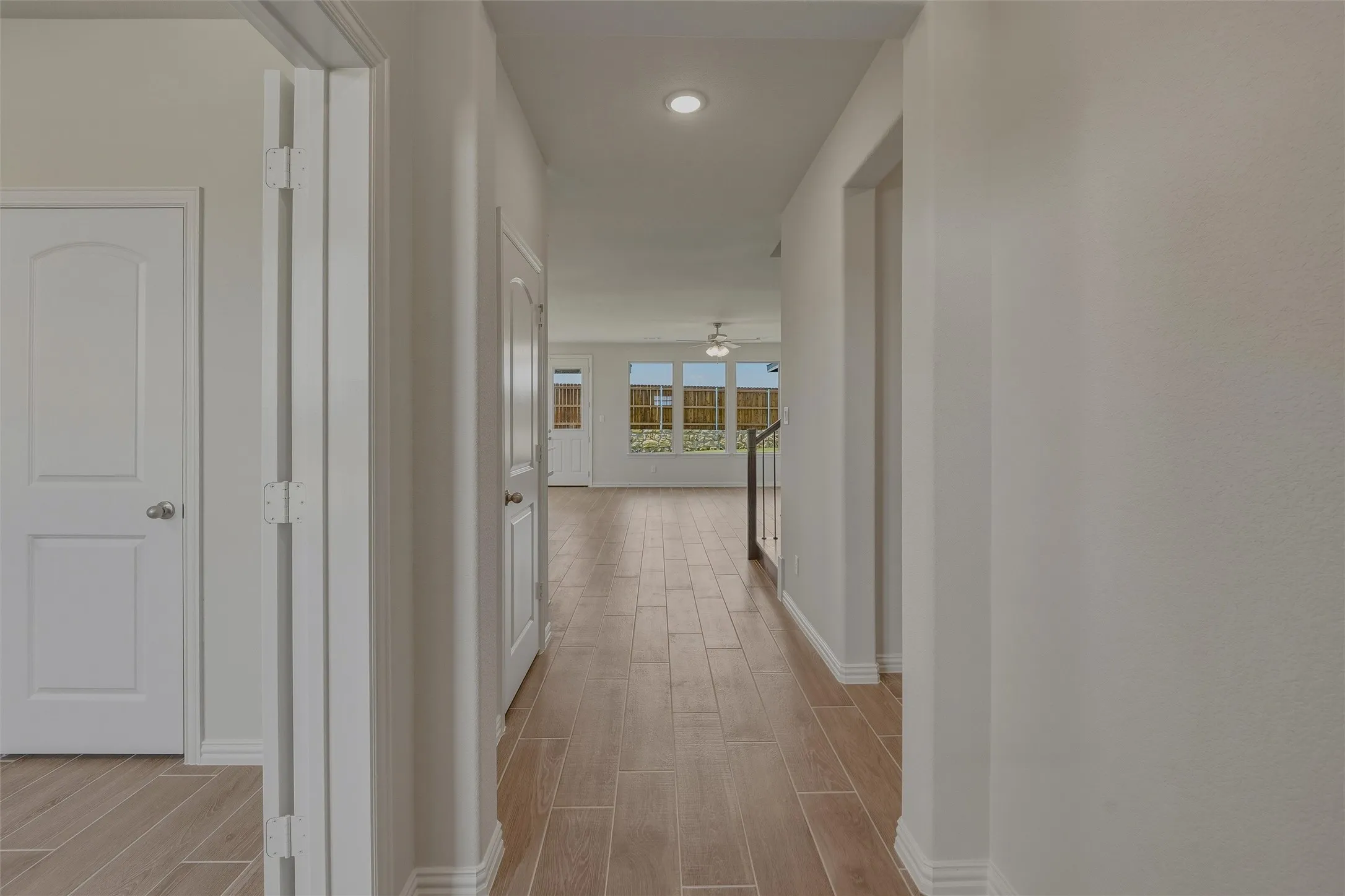 Elongated hallway with wood-finish flooring, white baseboards, and neutral wall tones