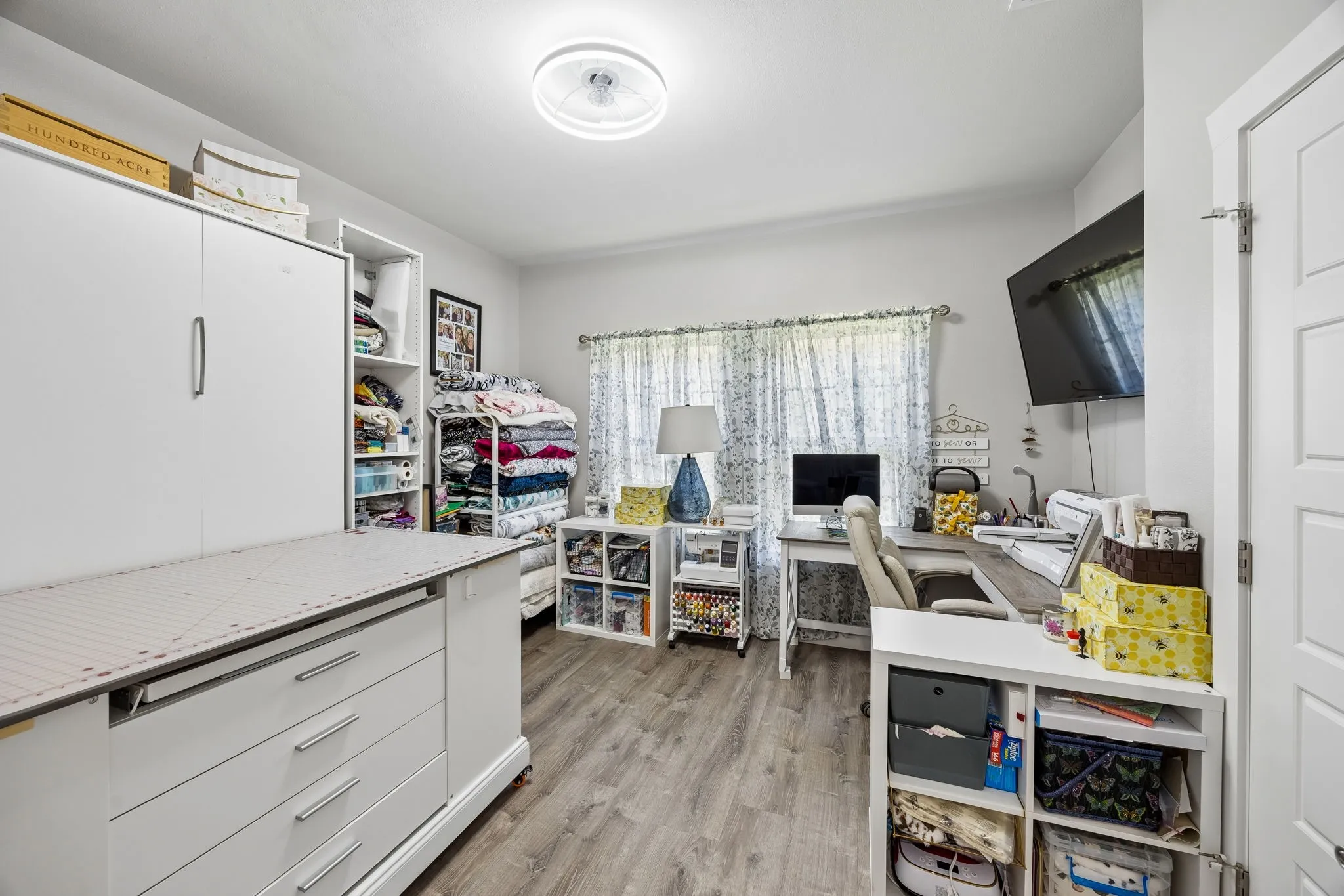 Multifunctional bedroom featuring wood-finish flooring, light grey wall paint, and white trim