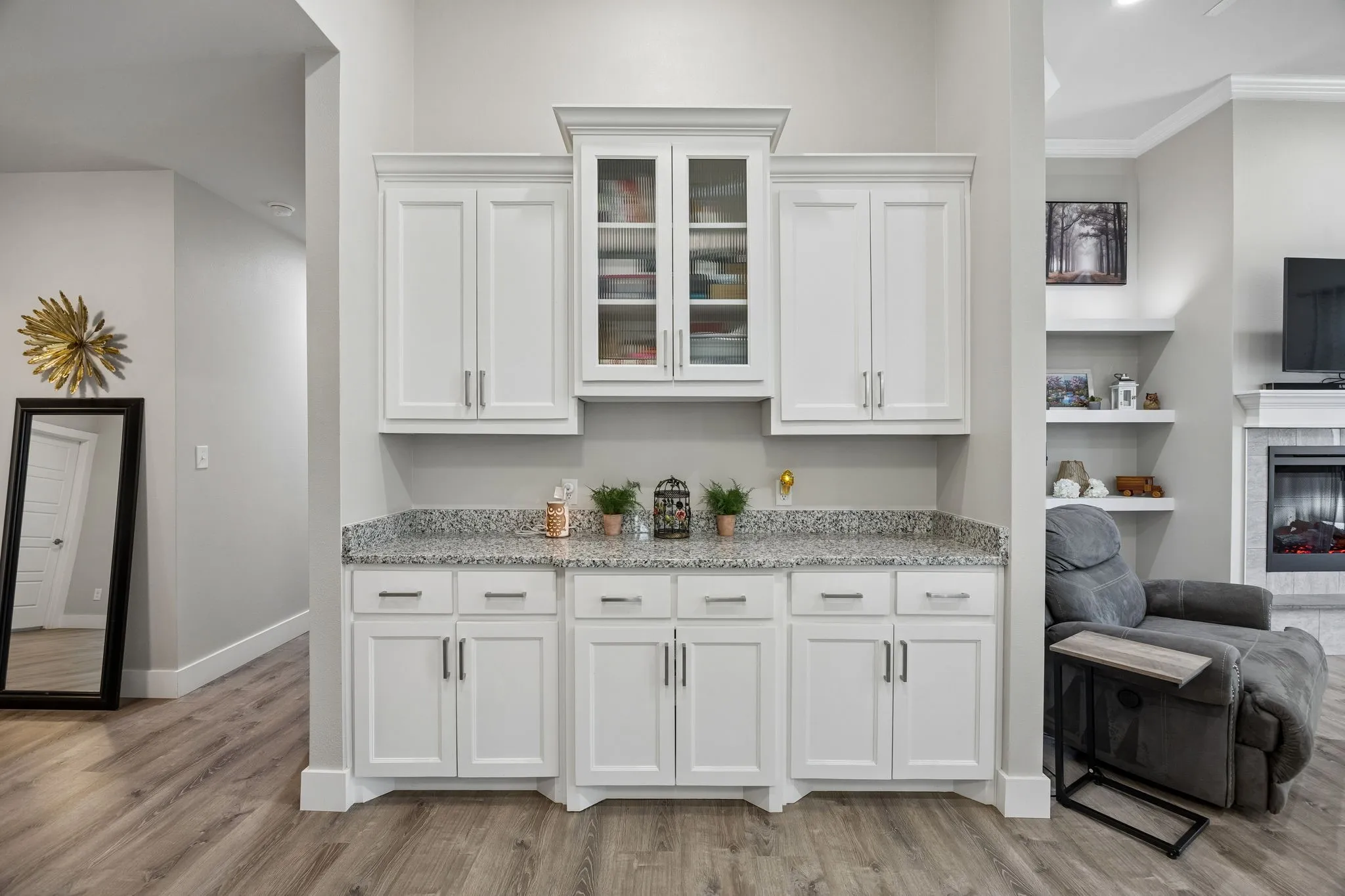Built-in cabinetry featuring white shaker-style doors, glass-front upper cabinets, and a speckled countertop