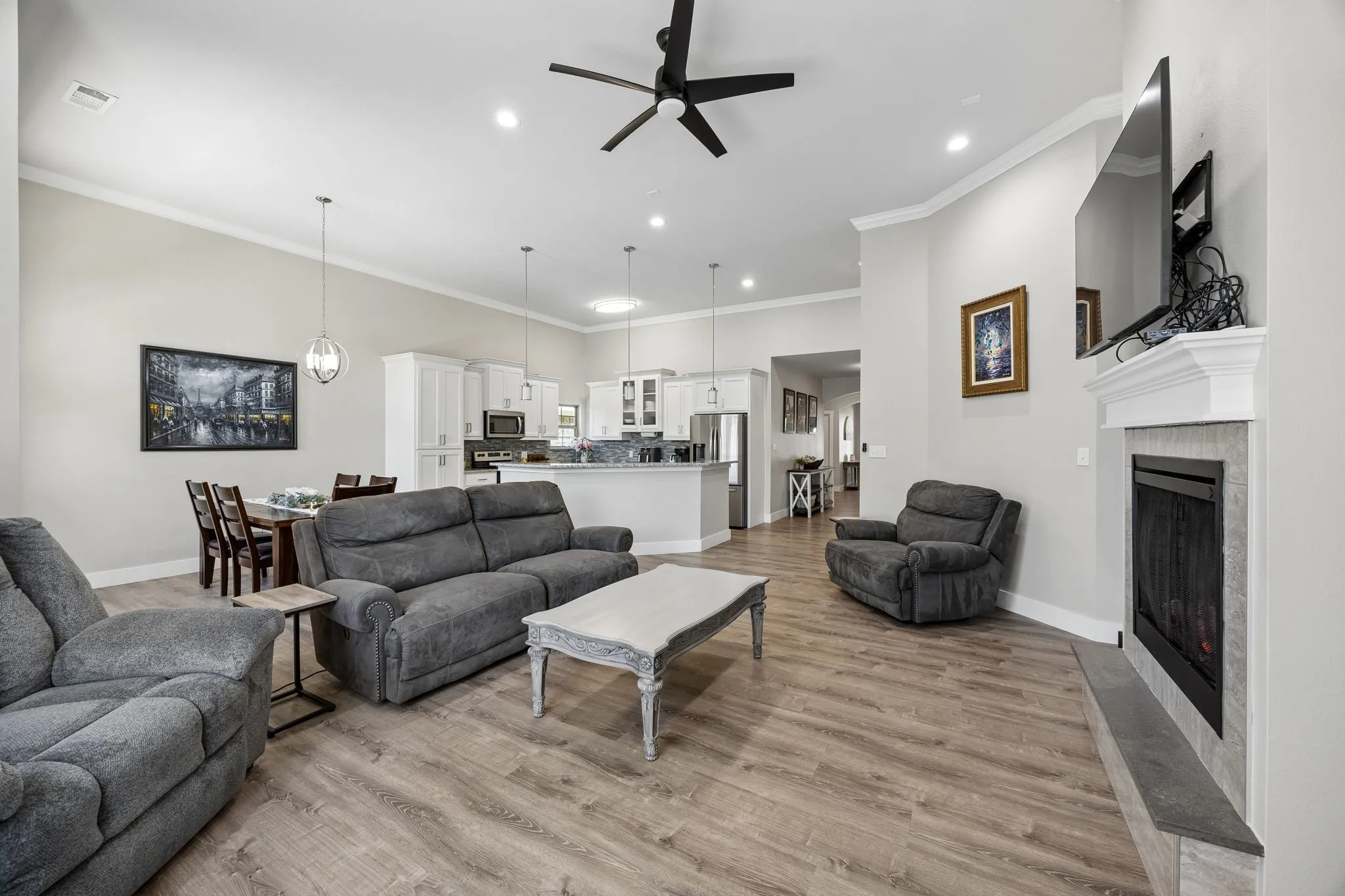 Spacious open-concept living area featuring wood-finish flooring, a ceiling fan, recessed lighting, and crown molding