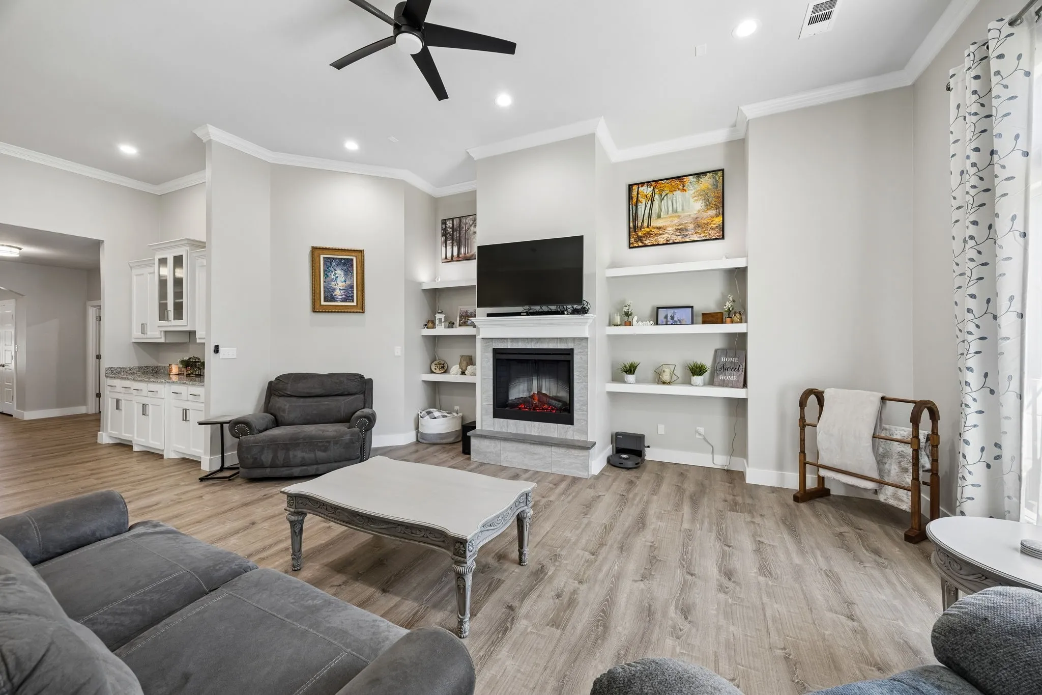 Living area featuring wood-finish flooring, a contemporary fireplace with a stone surround, and built-in shelving