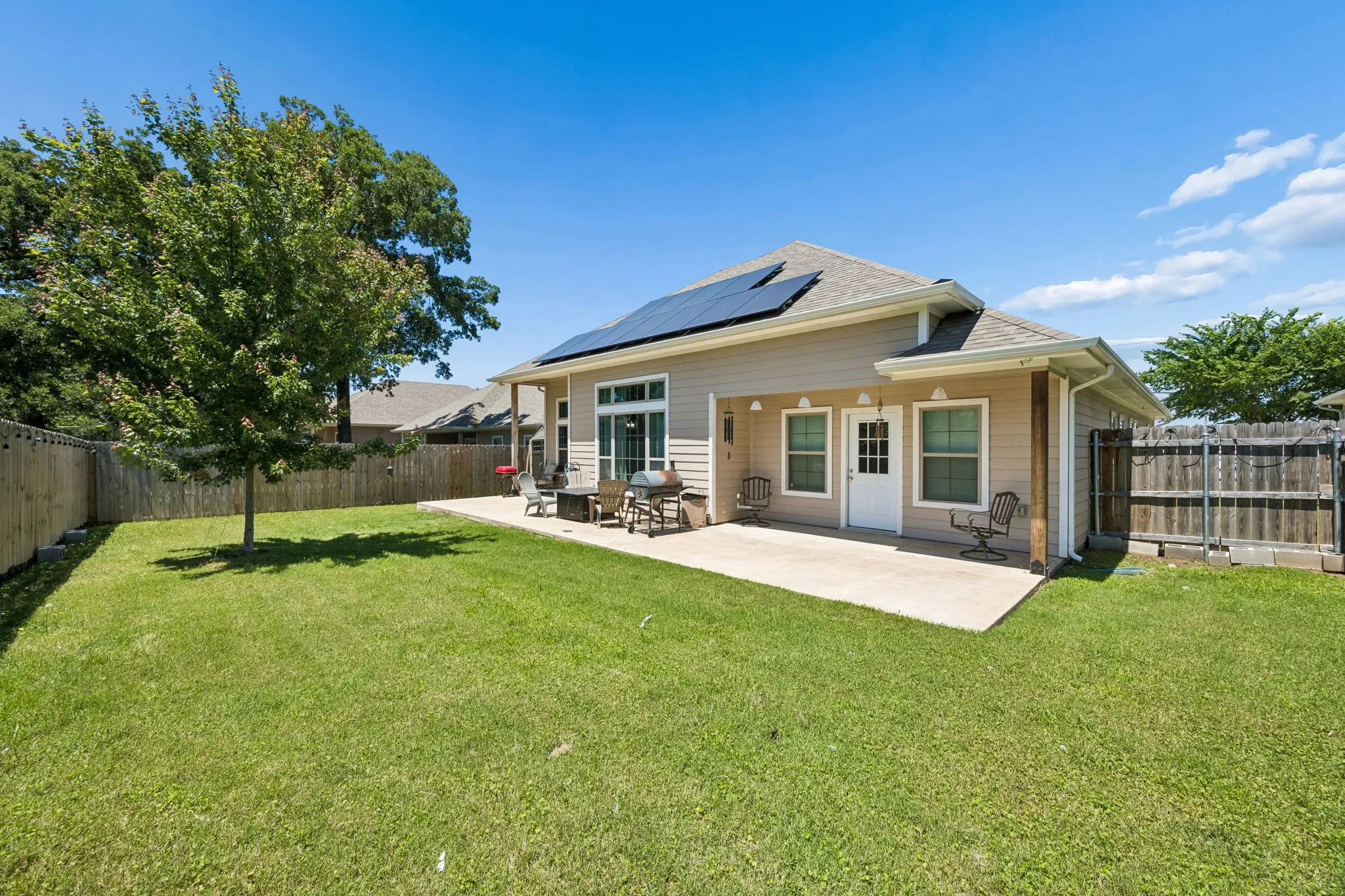 Expansive backyard featuring a manicured lawn, a large concrete patio, and a privacy fence