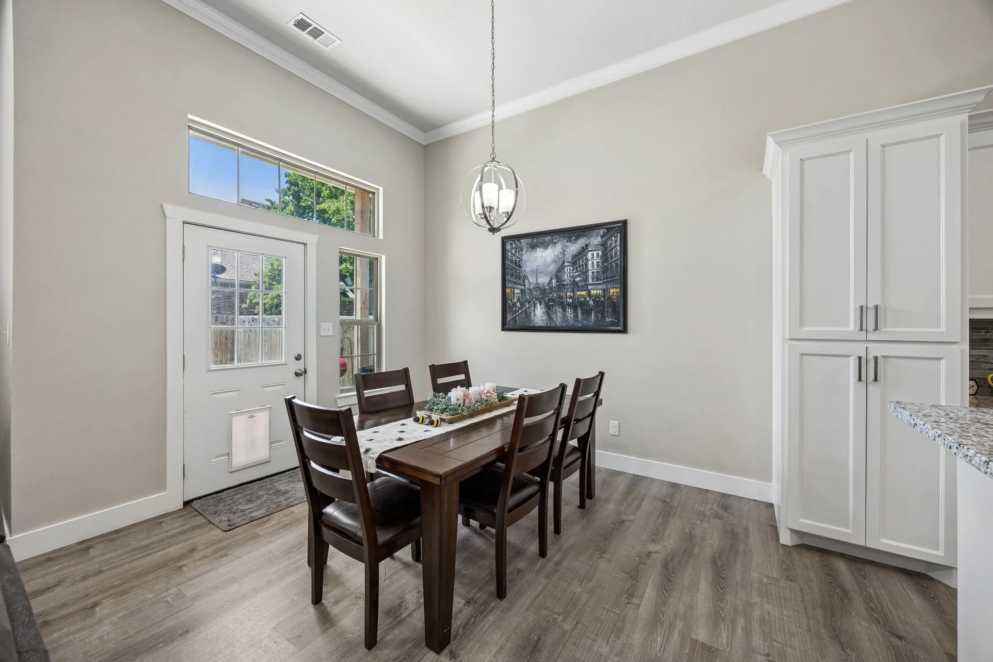Dining area with wood-finish flooring, high ceilings, and crown molding