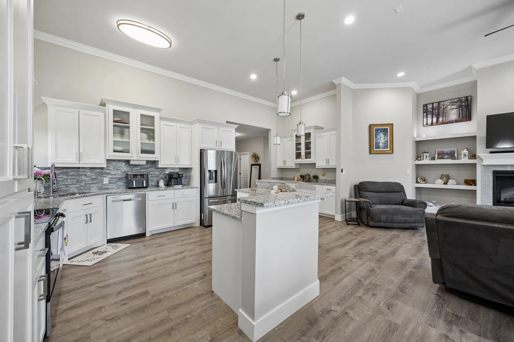 Open-concept living area featuring a kitchen with white cabinetry, stainless steel appliances, and granite countertops