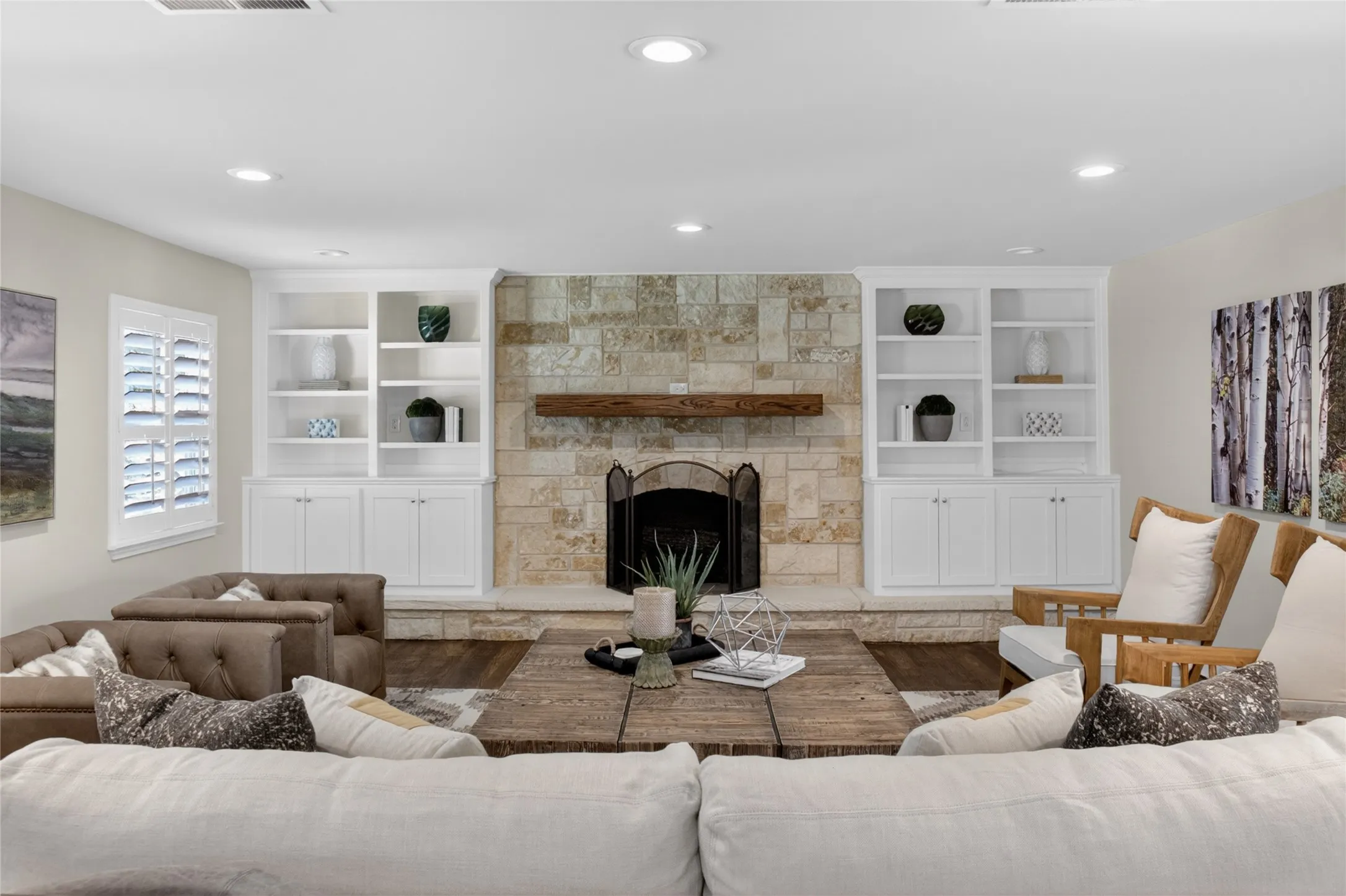 Another view of living area featuring the beautifully appointed built-in book shelves and a wood burning fireplace