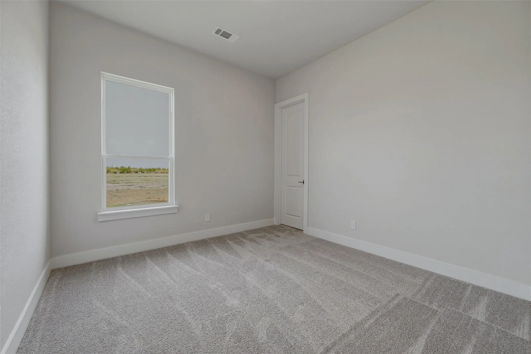 Carpeted room with a single window, white trim, and a panel door
