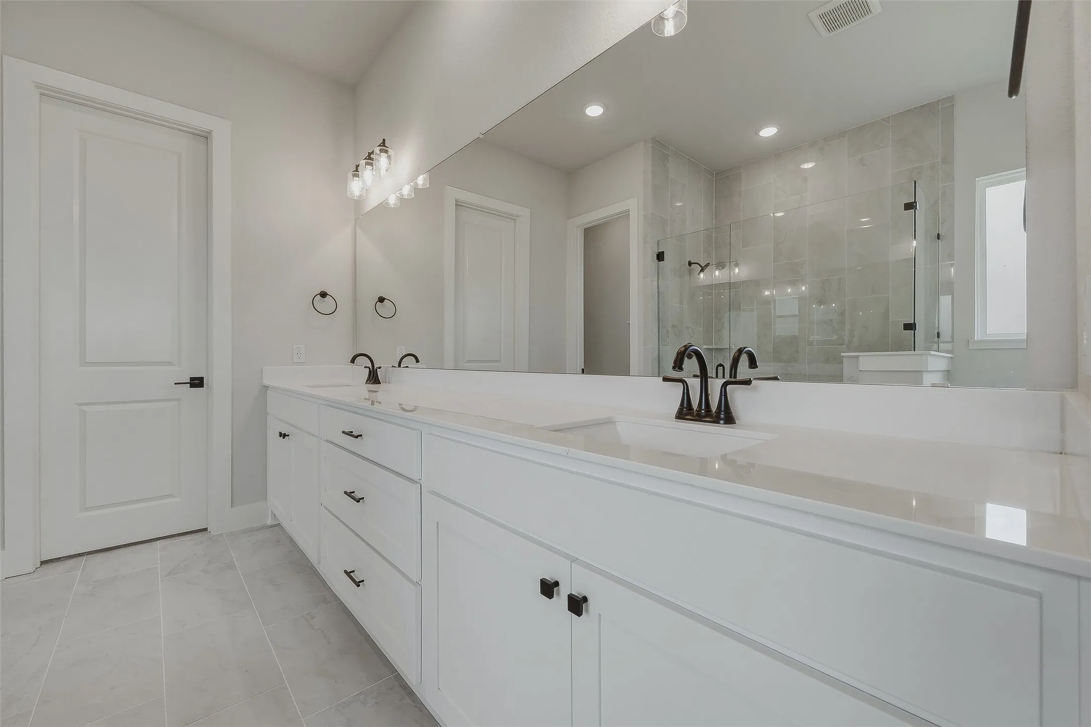 Dual sink vanity with white cabinetry and dark hardware