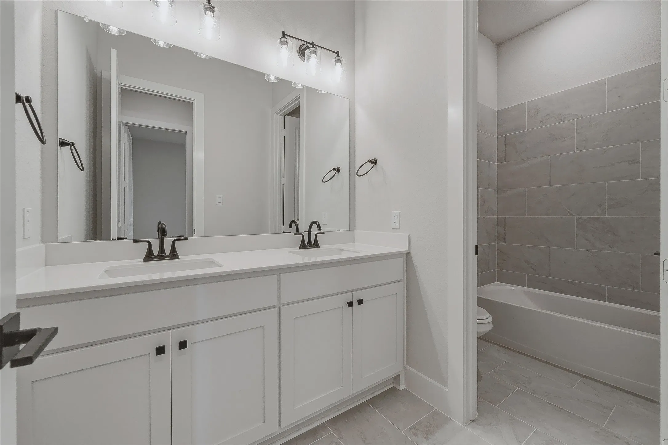 Dual vanity with white cabinetry, matte black fixtures, and integrated sinks