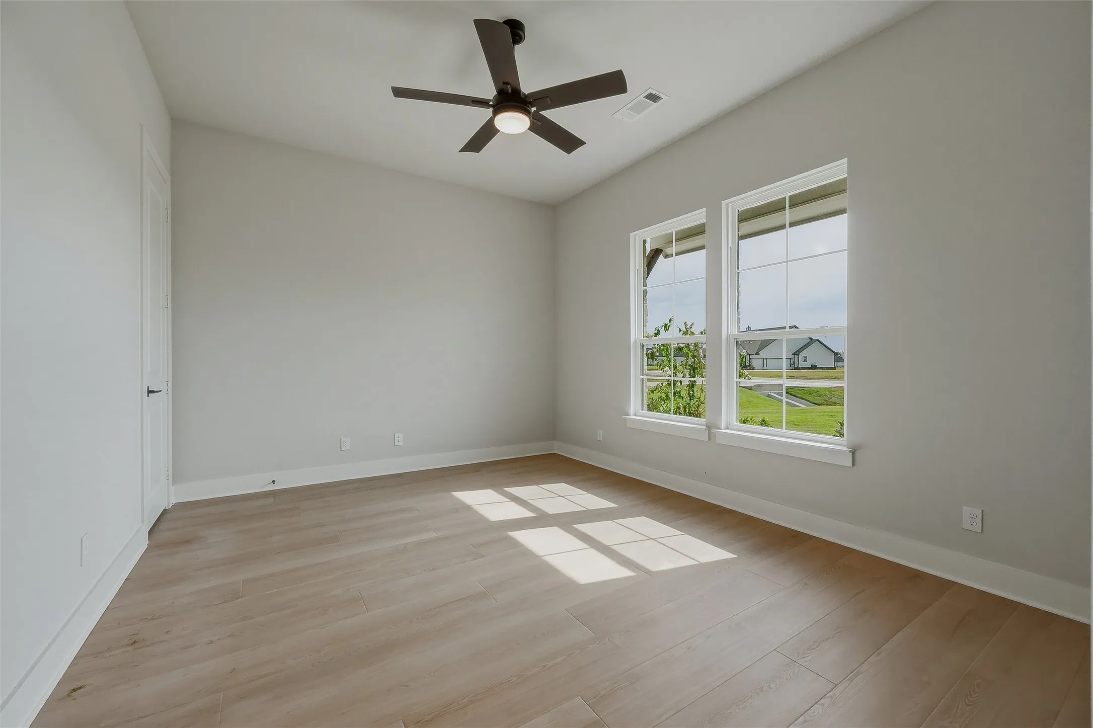 Vaulted ceiling with a ceiling fan, light wood-finish flooring, and two double-hung windows