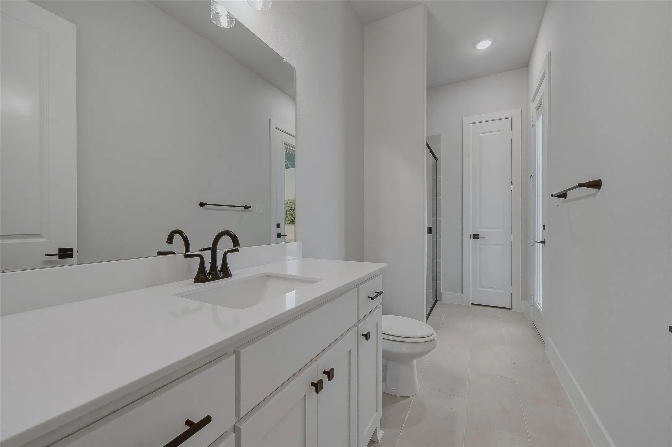 White vanity with a solid surface countertop, an integrated sink, and bronze-finish fixtures