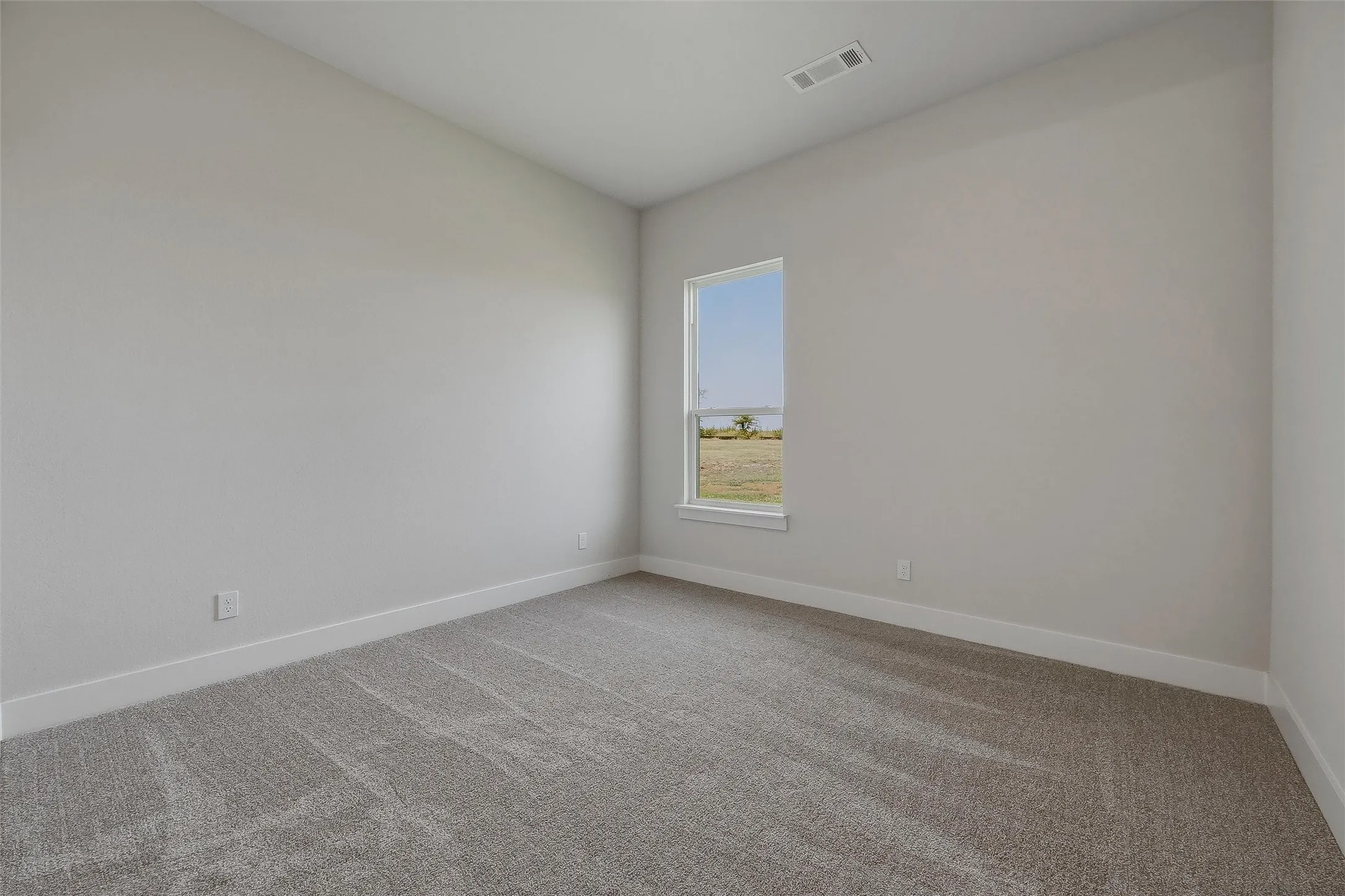 Textured carpeting with white baseboards and neutral wall paint