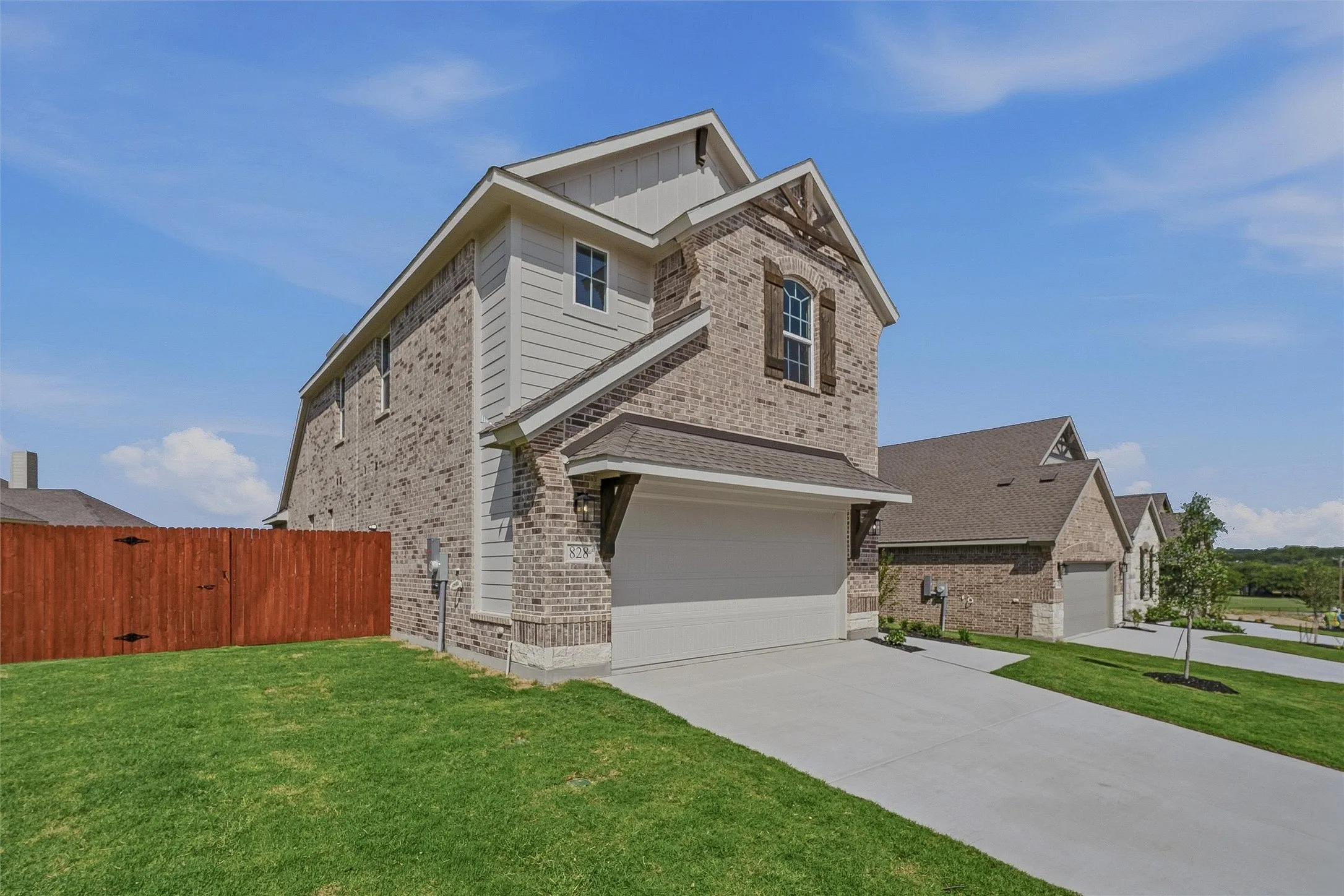 Brick and siding exterior featuring a prominent two-car garage with a decorative wood accent