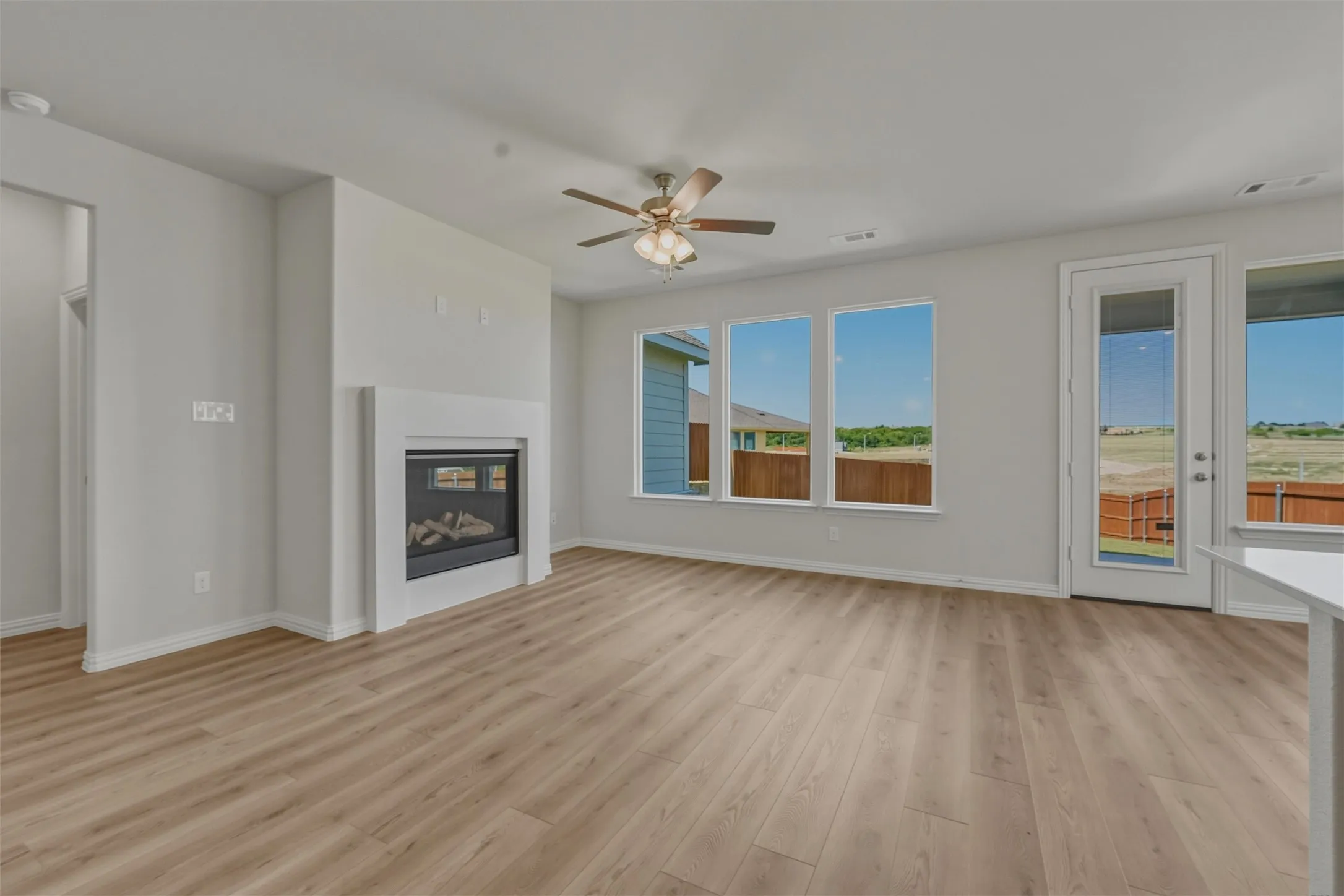 Living space featuring a white mantel fireplace, wood-finish flooring, and multiple windows